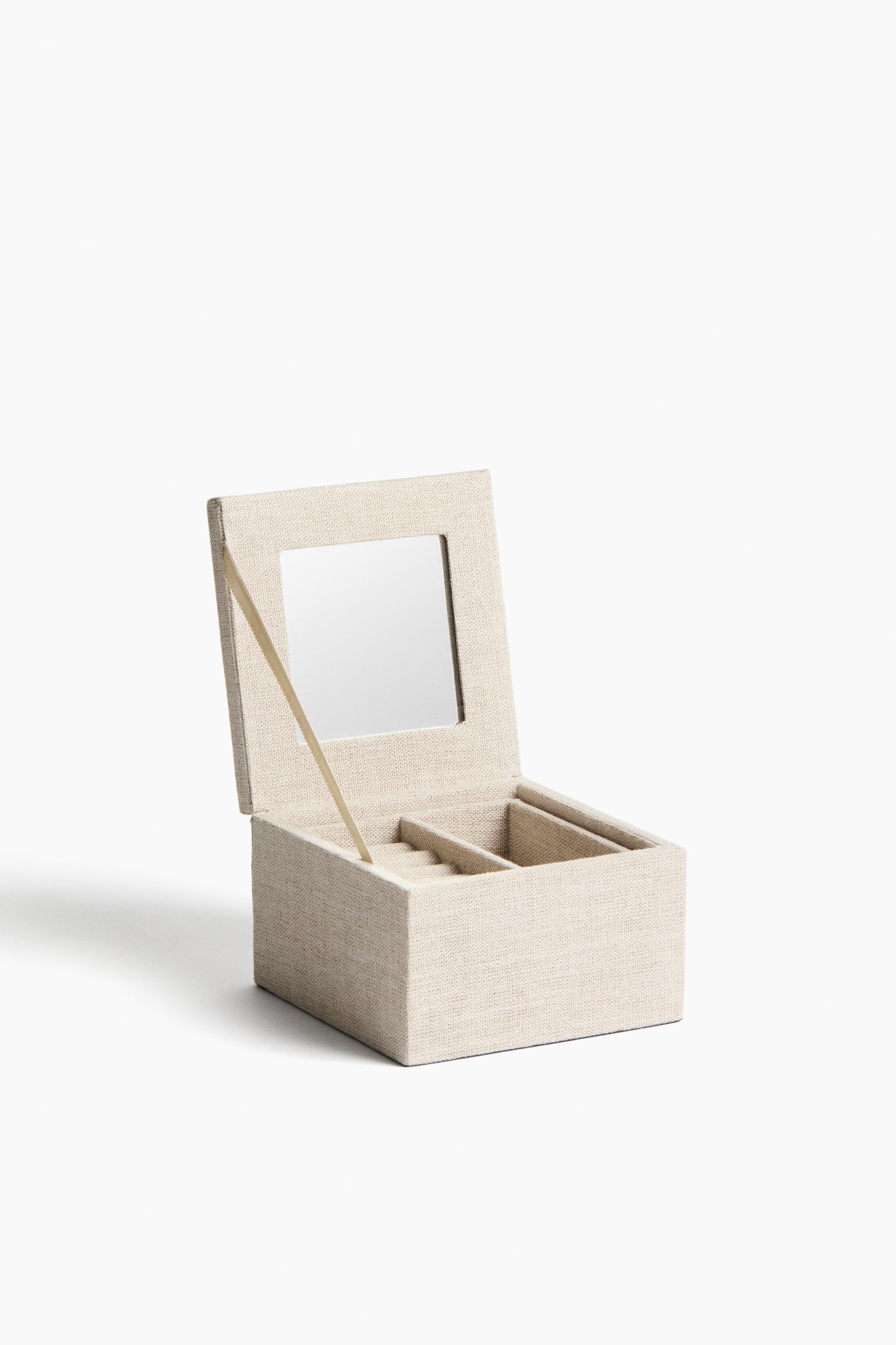 View larger image: A jewellery box features a textured, light beige fabric covering, presented from the front. Its open lid reveals a square mirror and is held by a light-coloured strap, while the interior shows a ring roll section on the left and two open compartments on the right.