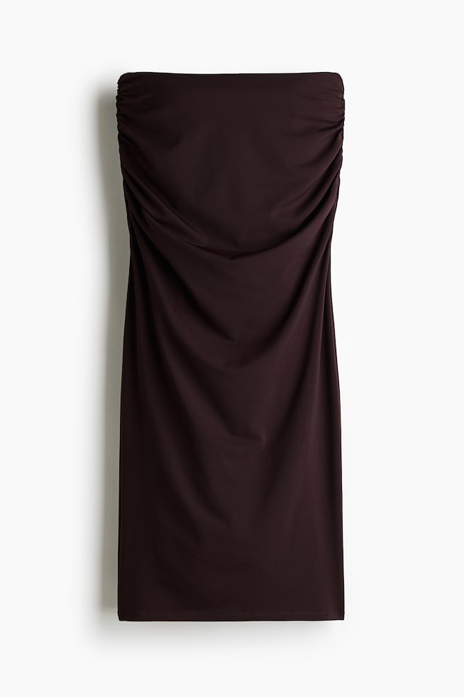Un vestido sin tirantes de color marrón oscuro muestra su parte frontal, con detalles fruncidos a lo largo del borde superior y un efecto drapeado en el corpiño delantero, extendiéndose en una silueta recta. - 1