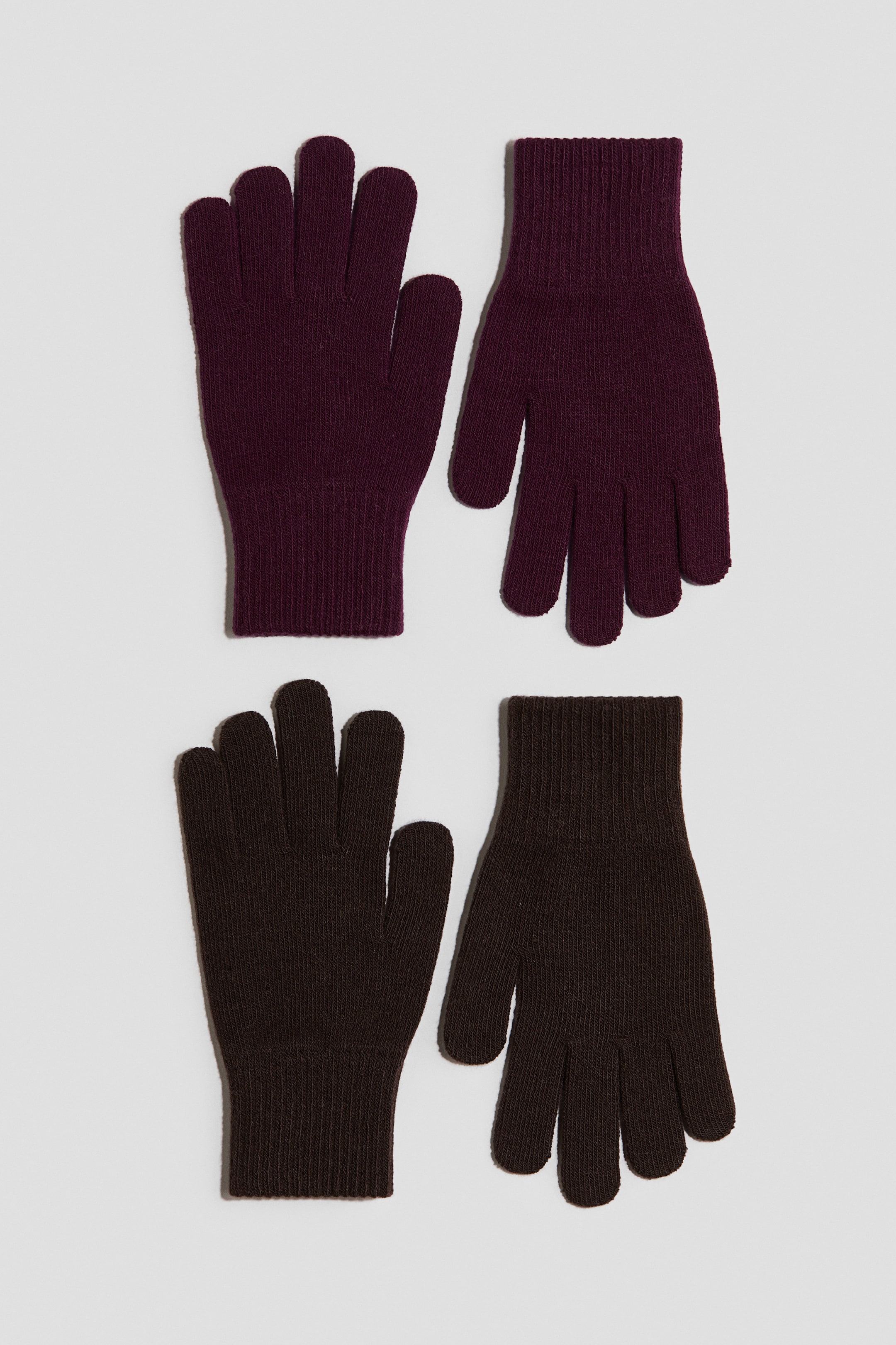 Ampliar la imagen: Los guantes están acomodados en dos pares, uno de color rojo oscuro y otro de color café oscuro. Cada guante está confeccionado en un tejido suave y fino, con puños acanalados, y está colocado plano con los dedos apuntando hacia arriba.