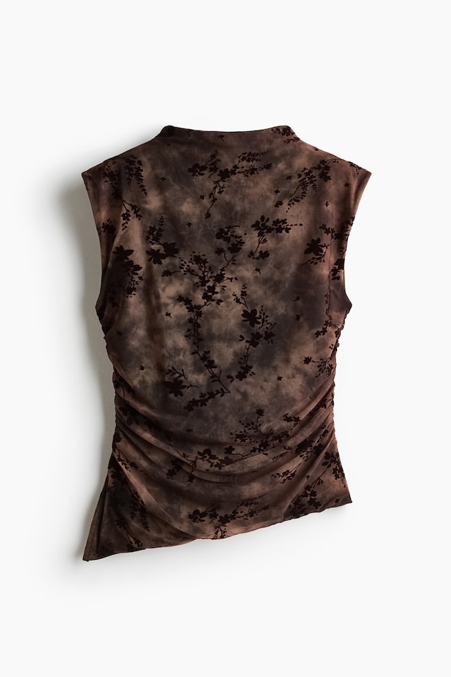 A sleeveless, fitted top in brown and black cloudy mesh showcases an all-over floral flock print from the front. The top features a high neck, gathered side seams that create draped ruching across the body, and a sloping asymmetrical hemline. - 1