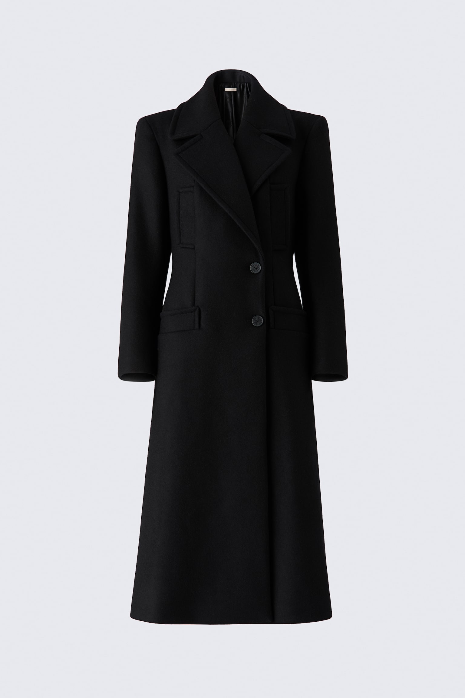 A structured, calf-length black coat is shown from the front, featuring wide peak lapels and a tailored waist that tapers to create an hourglass silhouette. The design showcases two front buttons, vertical welt chest pockets, and horizontal flap pockets at the hips.