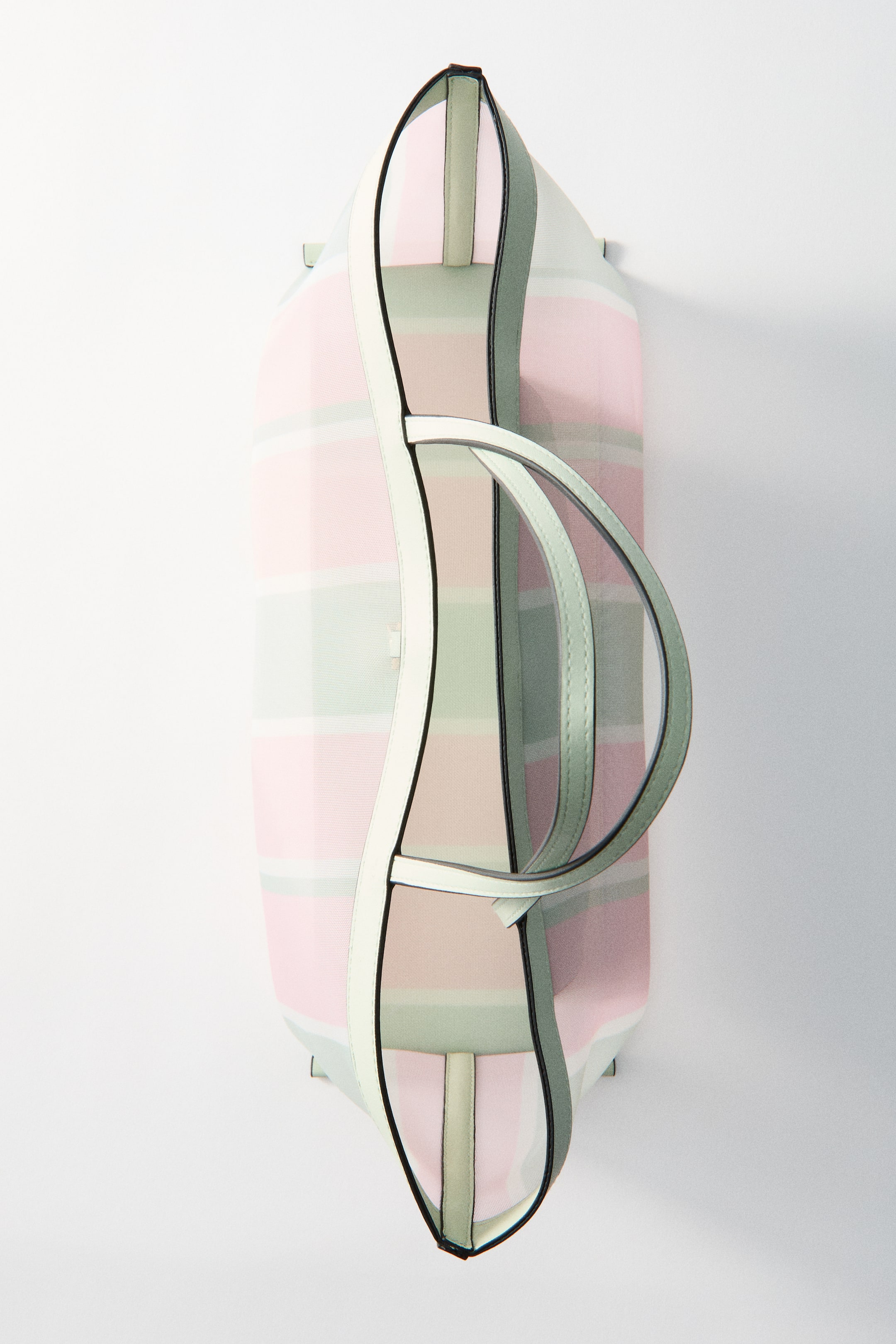 Ver imagen más grande: Un bolso shopper se presenta desde una vista cenital, con un exterior de malla que revela rayas horizontales en rosa claro, verde claro y crema. Muestra detalles en tejido recubierto, incluyendo asas más largas de color crema que delinean la parte superior, asas más cortas de color verde claro que se arquean sobre la apertura, y un pequeño cierre de gancho de color claro en el centro superior.