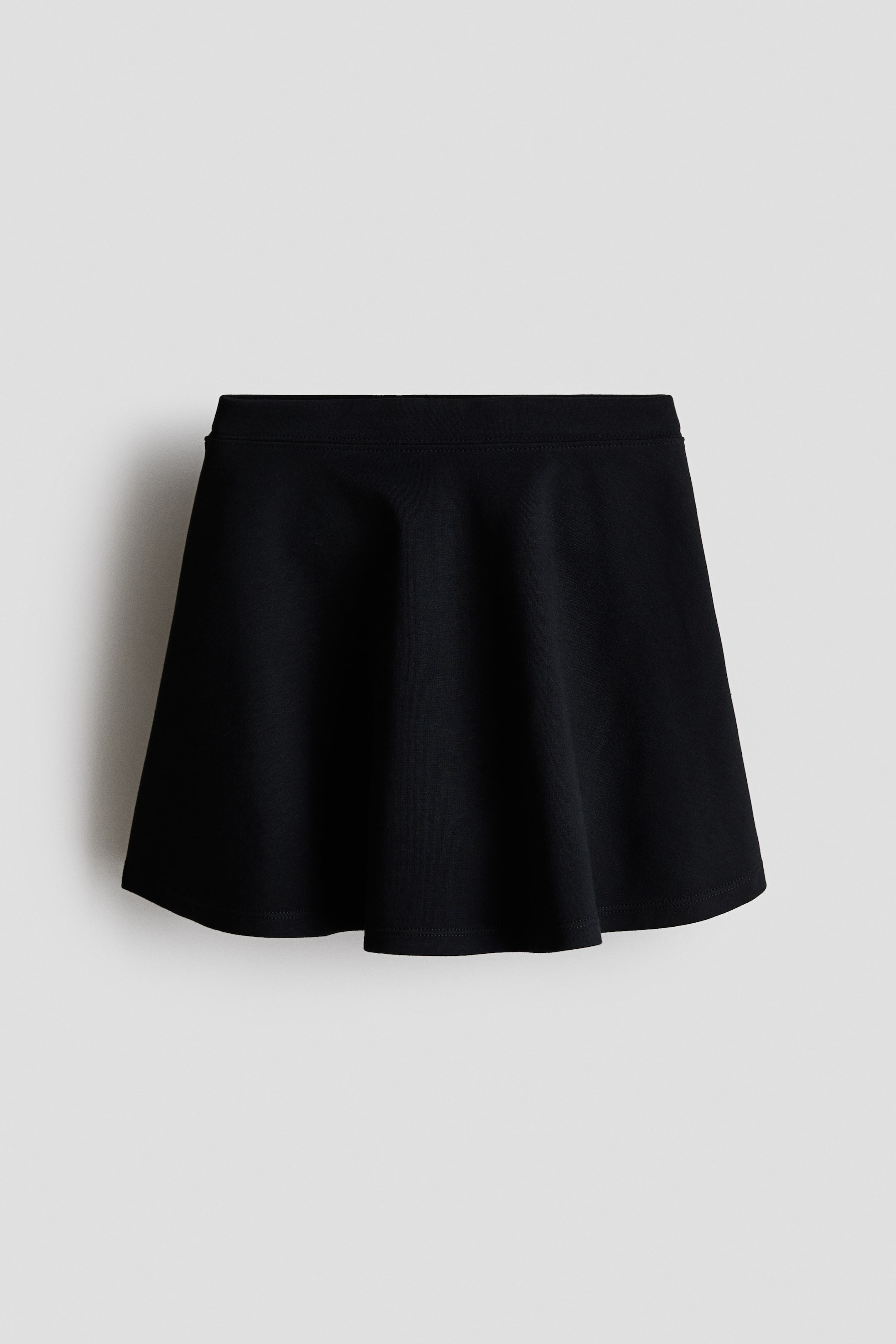 View larger image: A black skirt is shown from the front, featuring a smooth, covered waistband and a flared hem.
