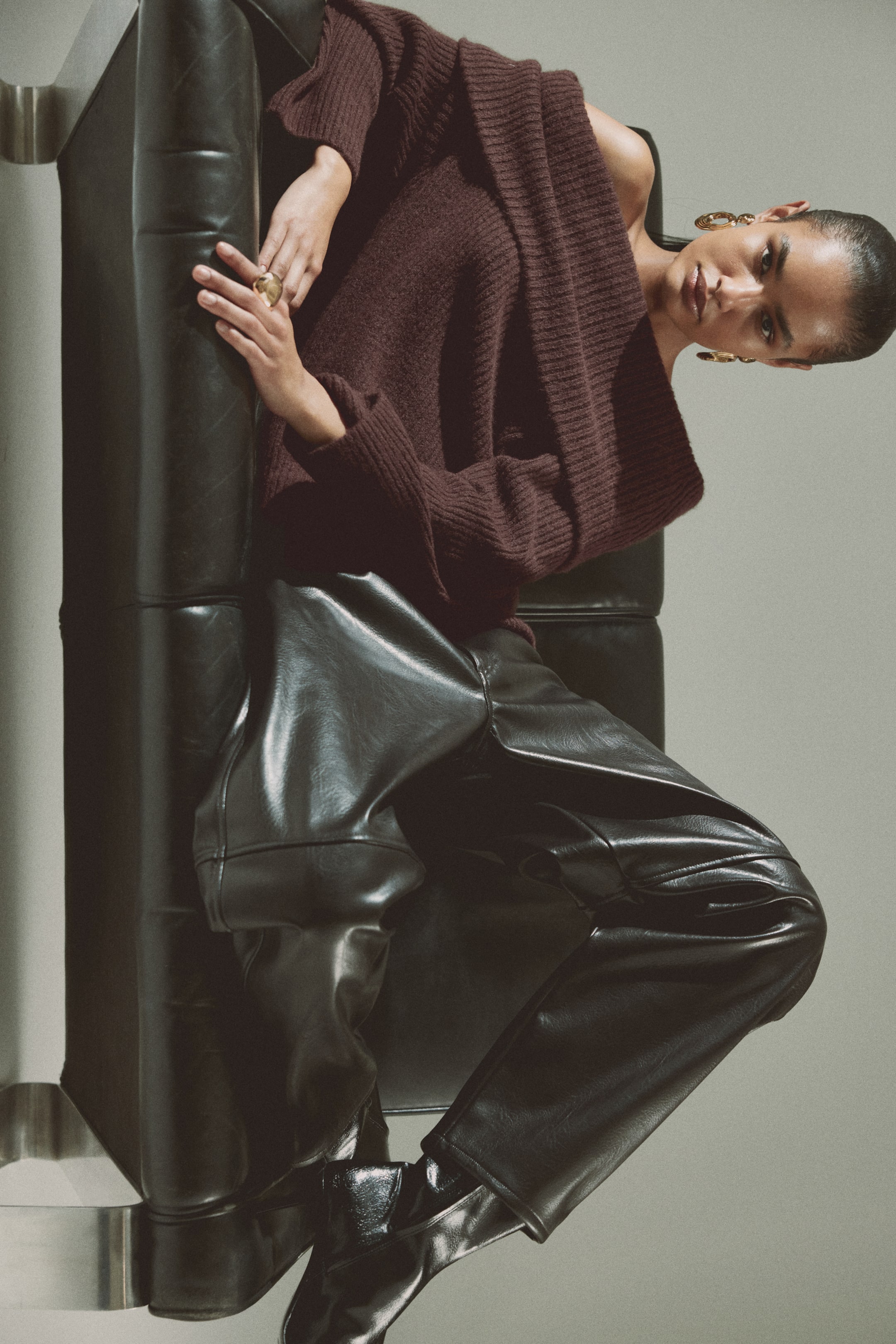View larger image: The model is wearing a dark red off-the-shoulder jumper crafted from a soft rib knit. It boasts a wide foldover at the top and long raglan sleeves.