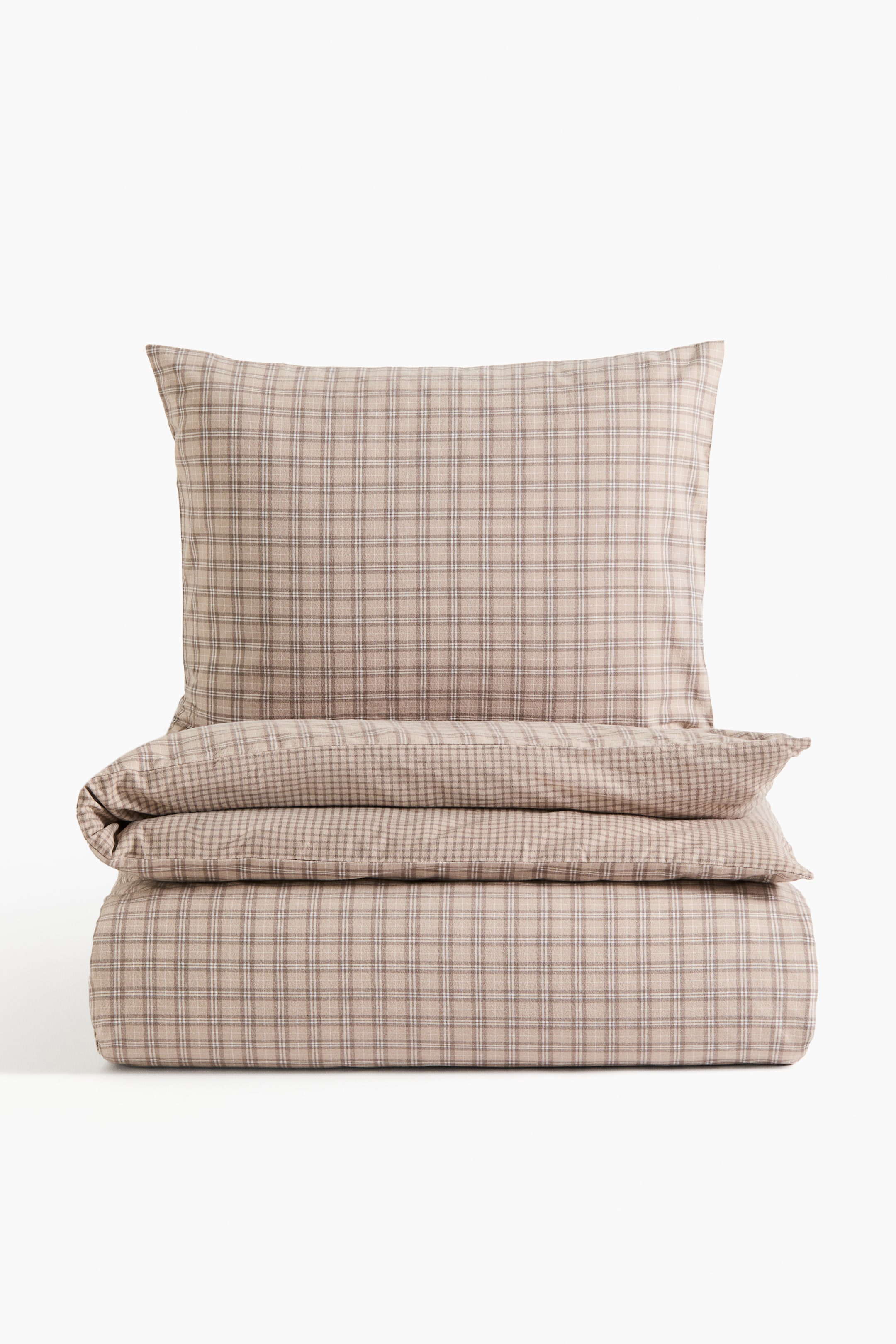 View larger image: A beige plaid bedding set features a pillowcase standing upright behind a neatly folded duvet cover, both with a brown and white grid pattern.