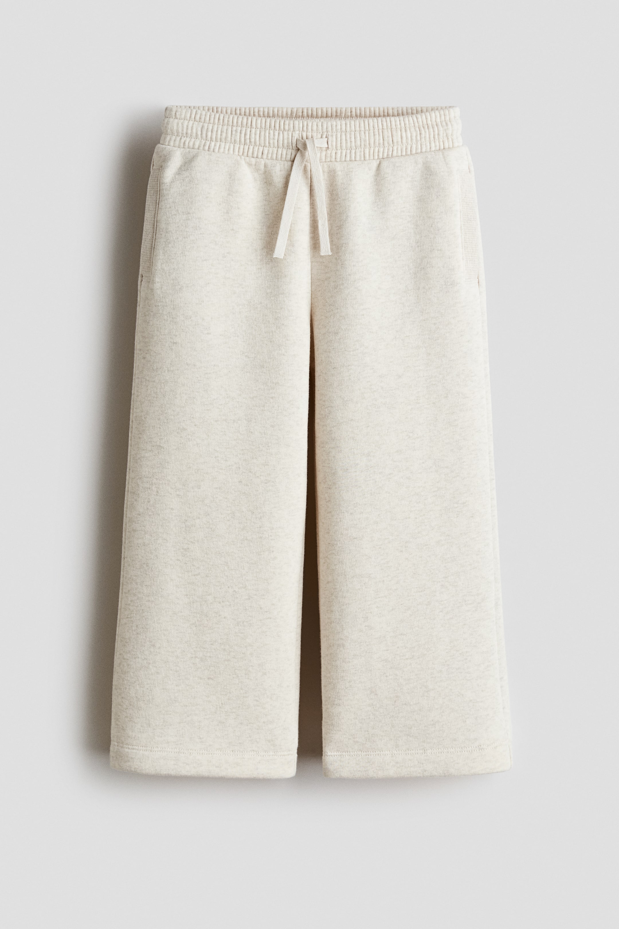 Ingrandisci l'immagine: I jogger sono mostrati frontalmente, con tessuto mélange chiaro, vita a coste elasticizzata con coulisse a vista, due tasche laterali e gambe ampie.