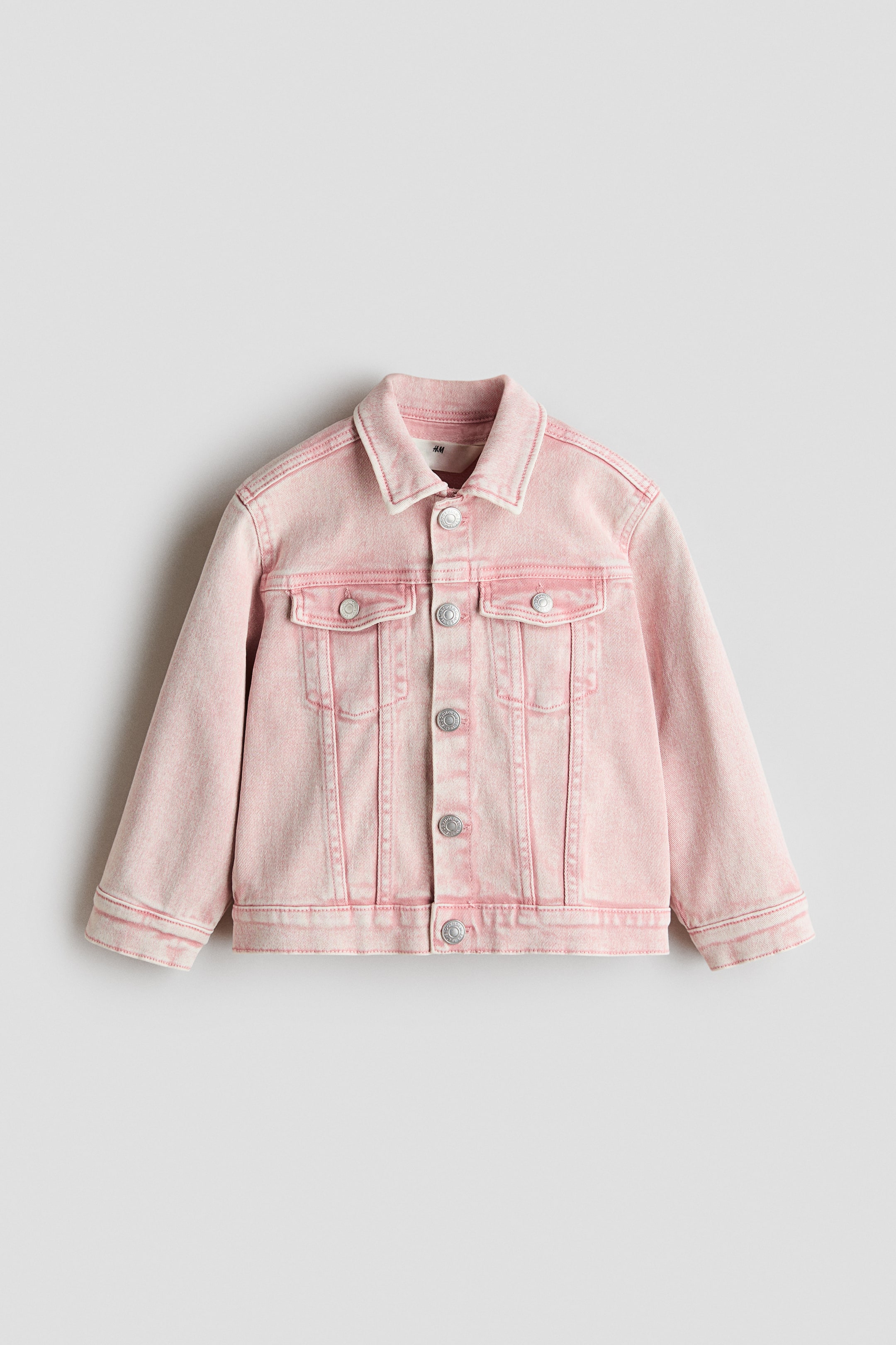 View larger image: A classic pink denim jacket is showcased from the front, featuring a turn-down collar, press-studs along the front and on the cuffs, and decorative chest pockets with flaps and press-studs.