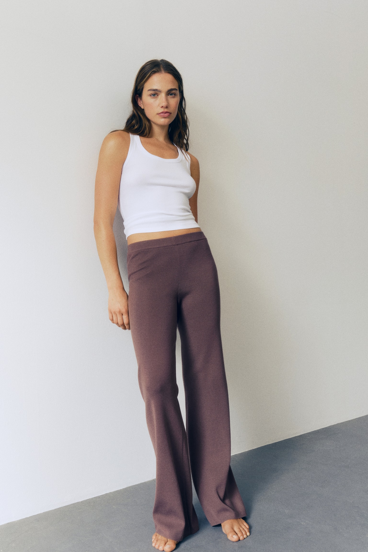 Brown knit wide-leg cropped trousers featuring a ribbed waistband and a subtle vertical line running down the centre of each leg, presented from a front-facing angle. - 1