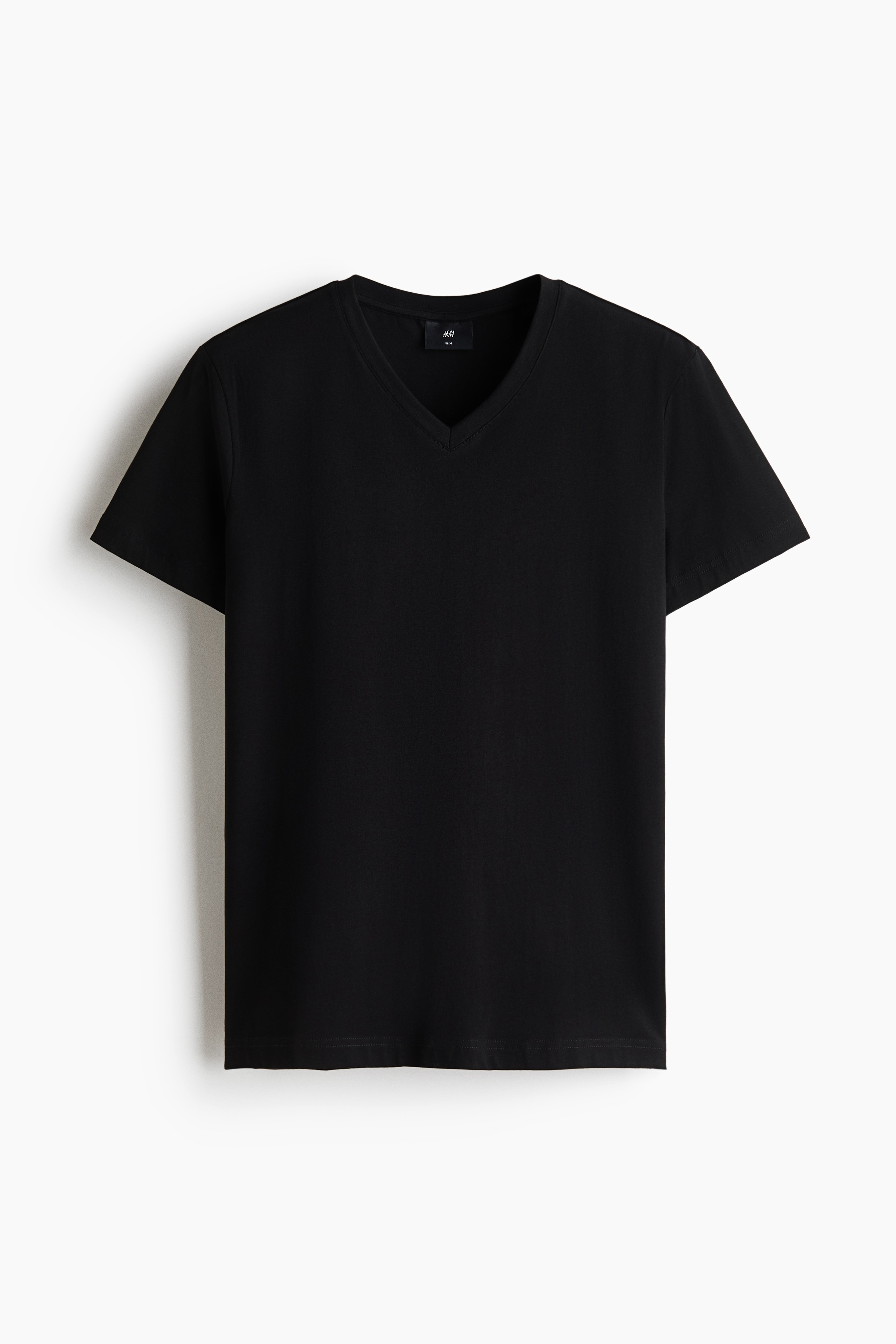 Le mannequin porte un t-shirt noir ajusté à col en V, rentré dans un pantalon marron foncé maintenu par une ceinture tressée noire. Ce tee-shirt léger en jersey de coton présente des manches courtes et une silhouette près du corps.