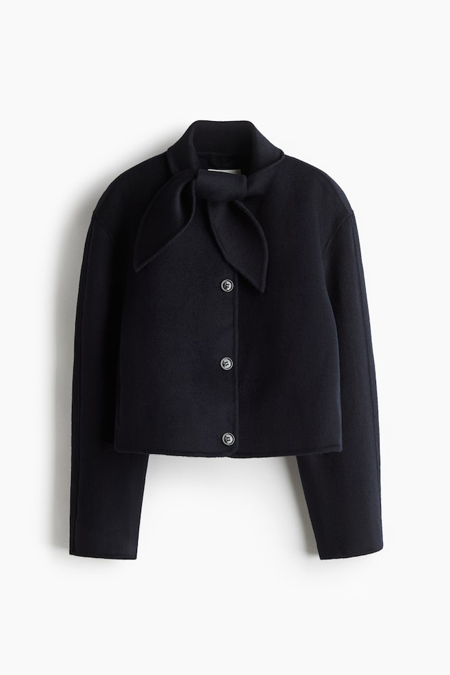 A short, dark felted wool blend jacket is shown in a FRONT view, featuring a scarf collar tied in a knot. Three round buttons are fastening the front closure, and the jacket is displaying gently dropped shoulders. - 1