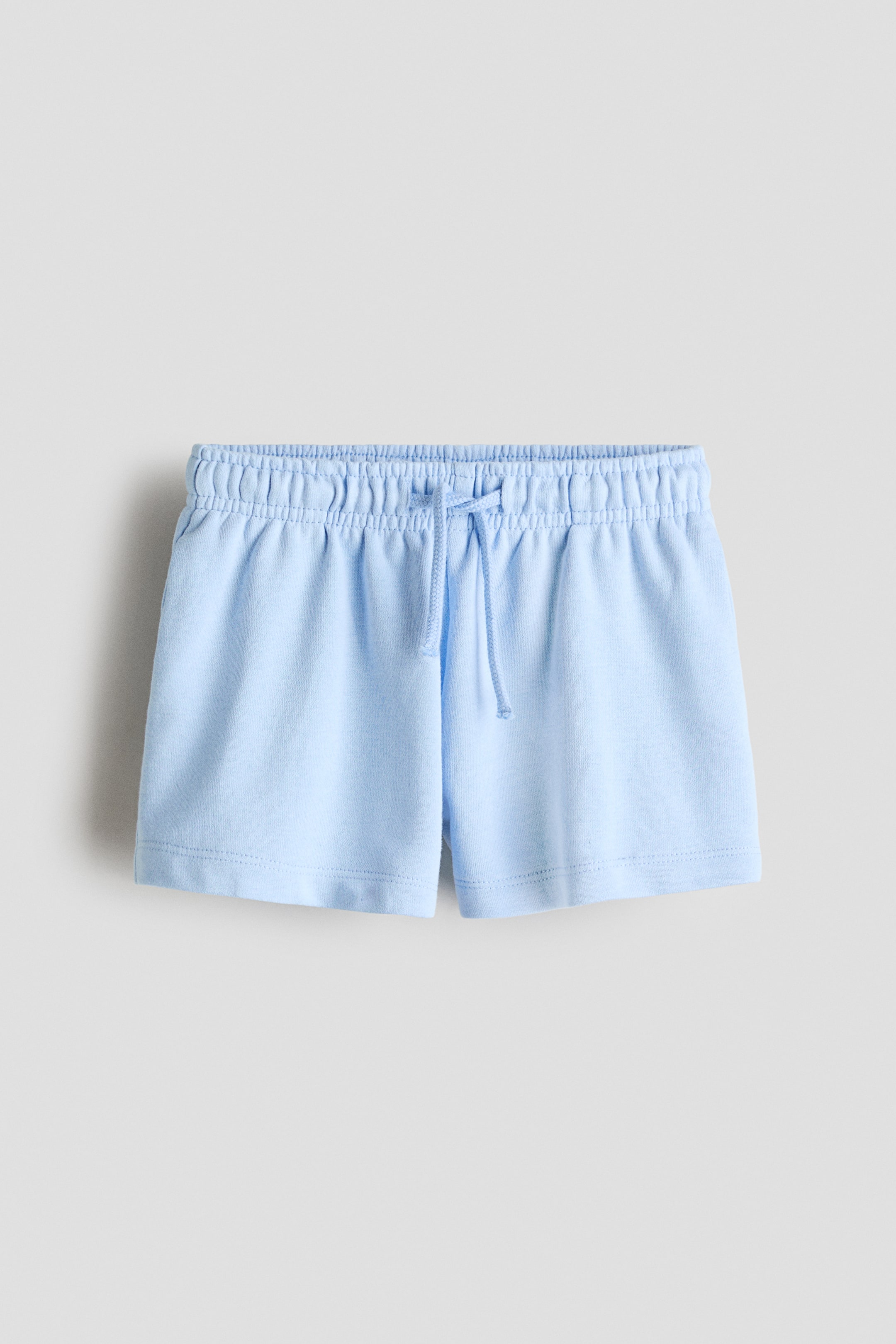 View larger image: Light blue shorts are shown from the front, featuring an elastic, gathered waistband with a tied drawstring, and showcasing a soft, sweatshirt fabric texture.
