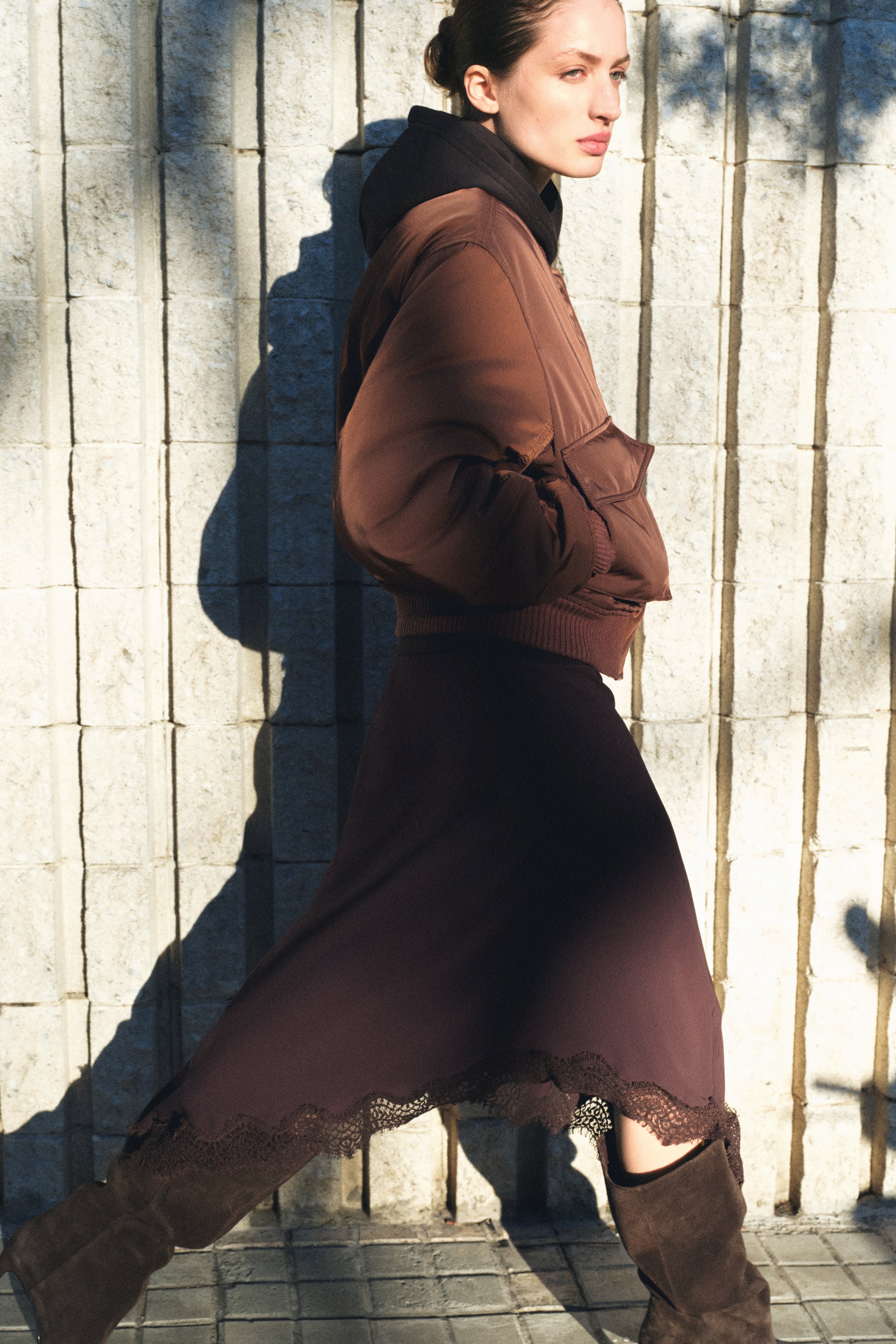 Προβολή μεγαλύτερης εικόνας: Η μοντέλο φοράει ένα καφέ μπουφάν bomber με επένδυση, το οποίο έχει τα χέρια της στις τσέπες για ζέσταμα. Το μπουφάν διαθέτει μπροστινές τσέπες με καπάκια, χαμηλωμένους ώμους και ριμπ στις μανσέτες και στο στρίφωμα, και είναι φορεμένο πάνω από ένα μαύρο φούτερ.