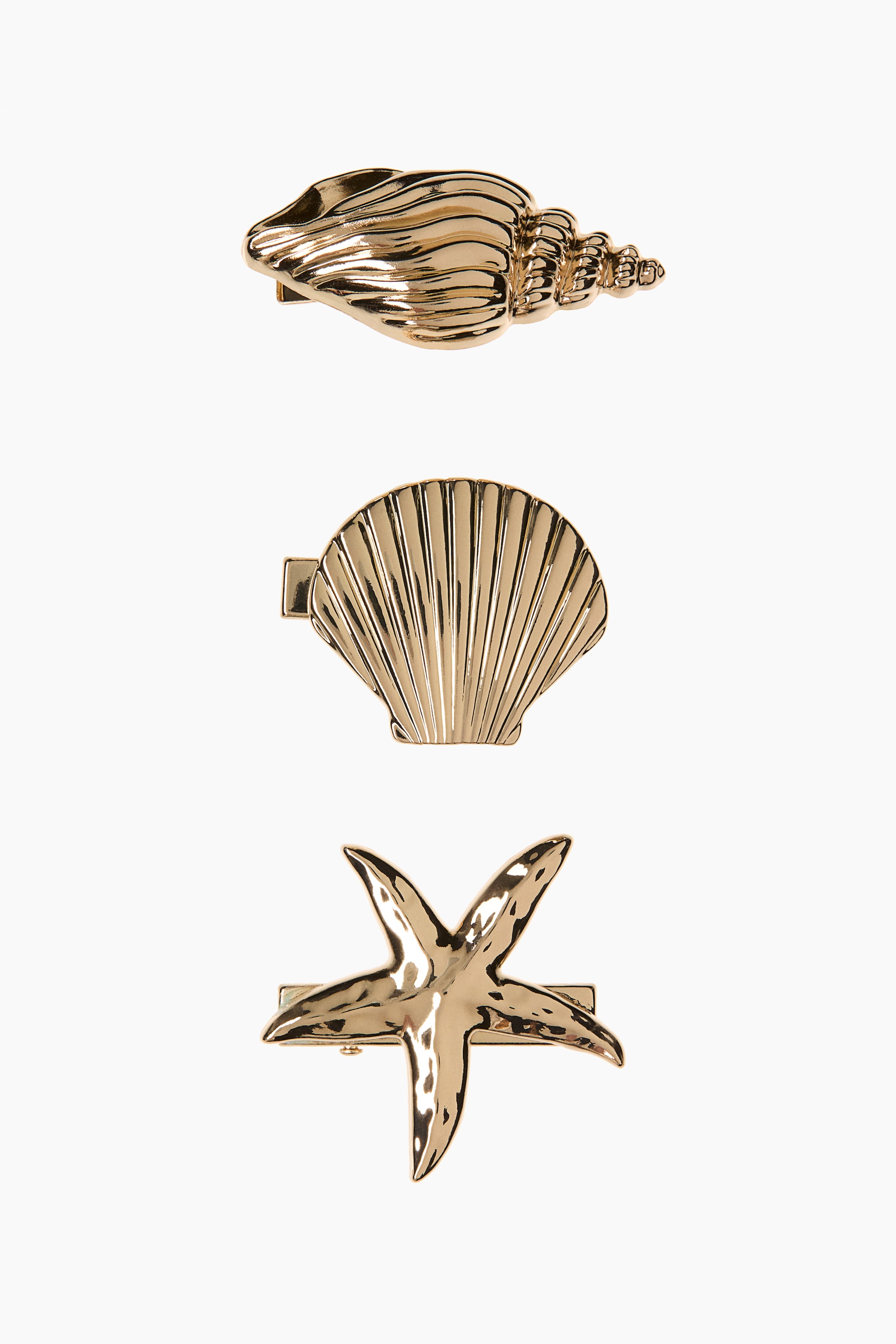 Ingrandisci l'immagine: Le mollette per capelli presentano design a tema marino in metallo color oro. La molletta superiore mostra una conchiglia a coste, quella centrale una conchiglia a ventaglio con scanalature radiali e quella inferiore una stella marina a cinque braccia con texture.