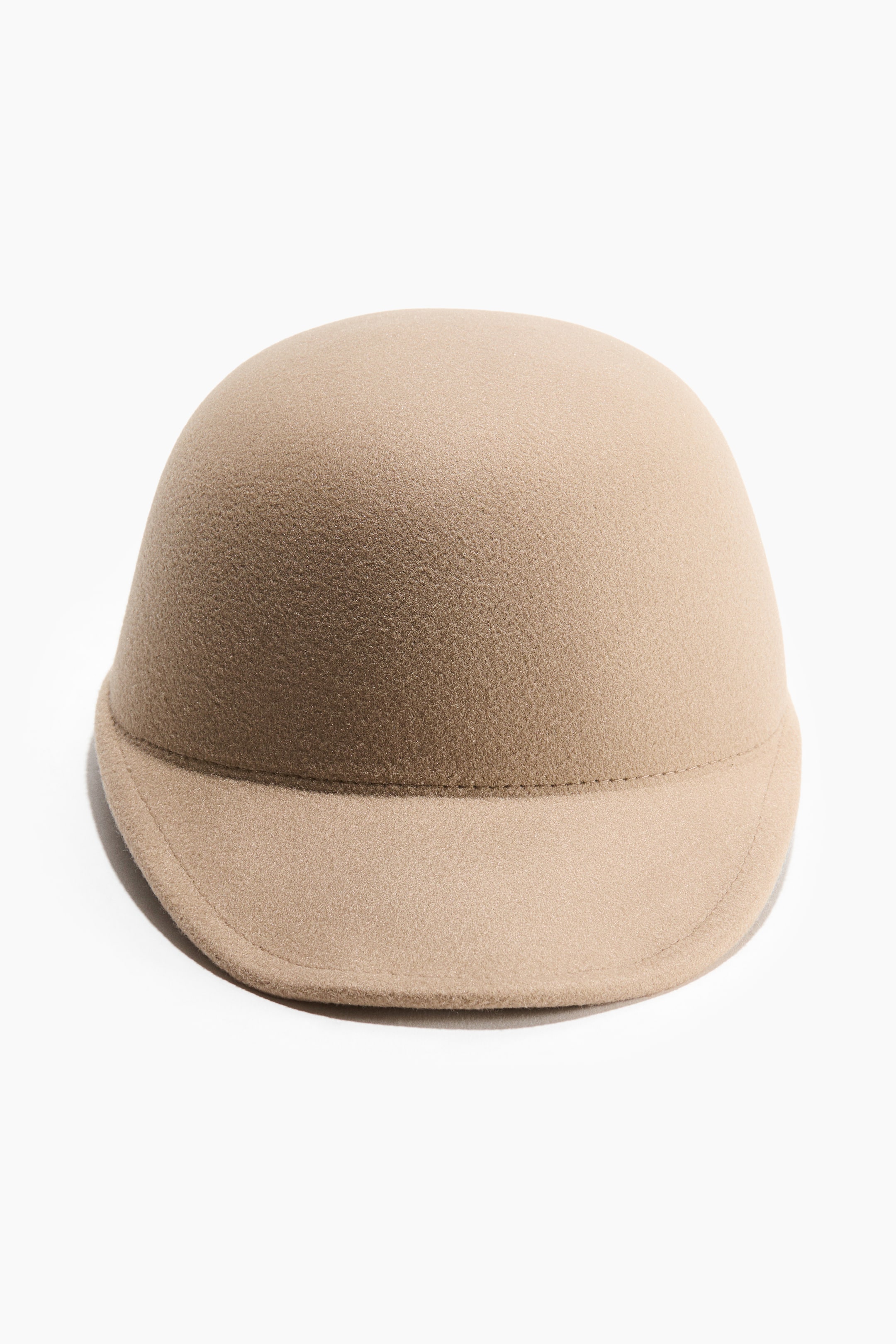 Grotere afbeelding bekijken: Een beige hoed is van voren te zien, met een gladde, koepelvormige kroon en een korte, licht gebogen rand. Een zichtbare naad scheidt de kroon van de rand, en de hoed heeft een zachte, pluizige textuur.