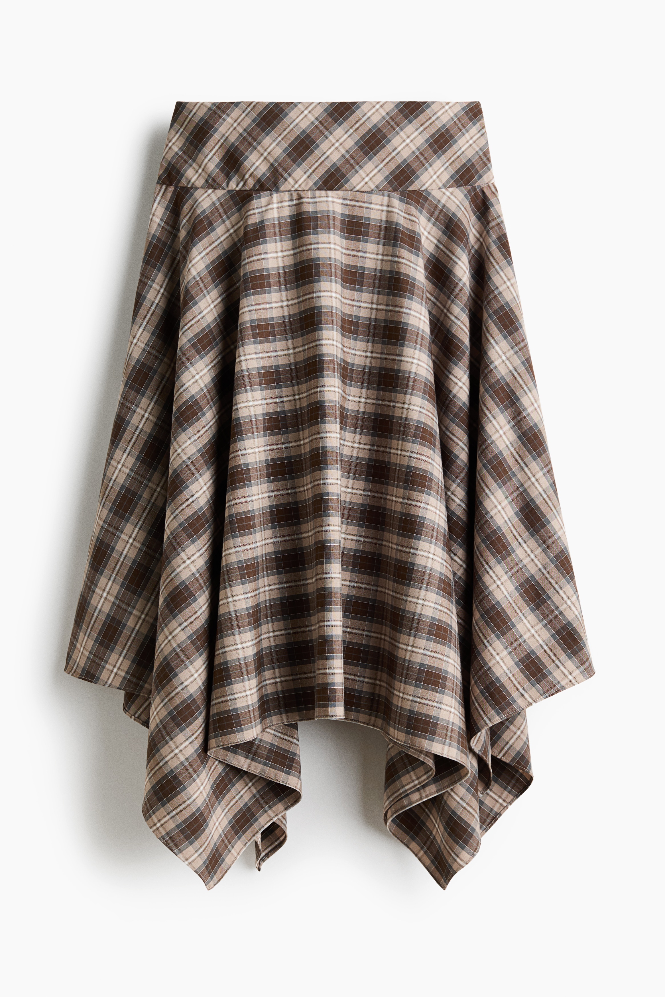The model is wearing a calf-length skirt in a brown and beige plaid woven fabric, featuring a wide, double-layered waistband and an asymmetrical handkerchief hem. The skirt is styled with a matching short-sleeved plaid top and low-heeled sandals.