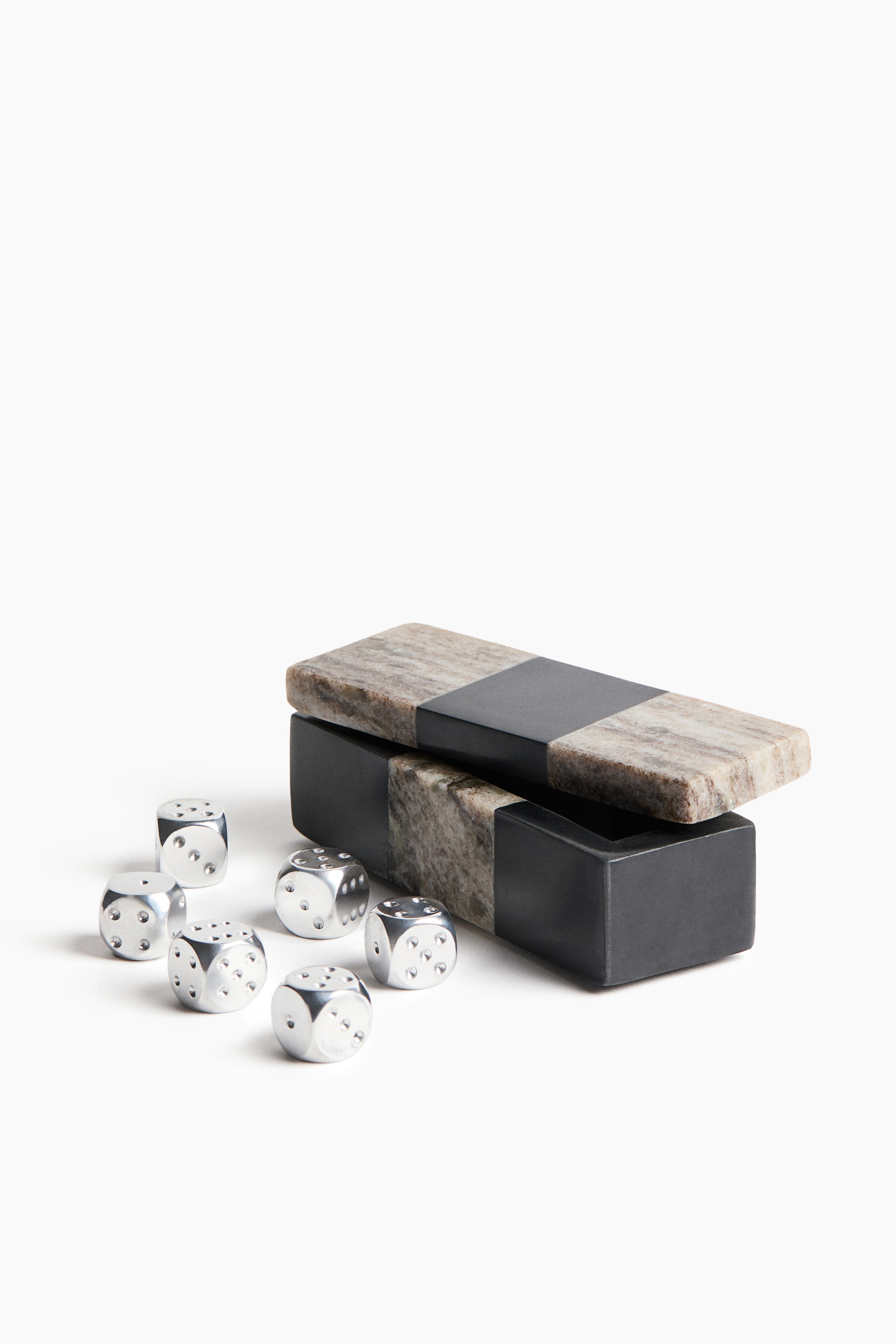 View larger image: A rectangular decorative box featuring a colour-blocked design in black and textured grey marble is shown from a front three-quarter angle, with its lid resting askew. Six metallic silver dice with rounded corners are scattered in front of the box.