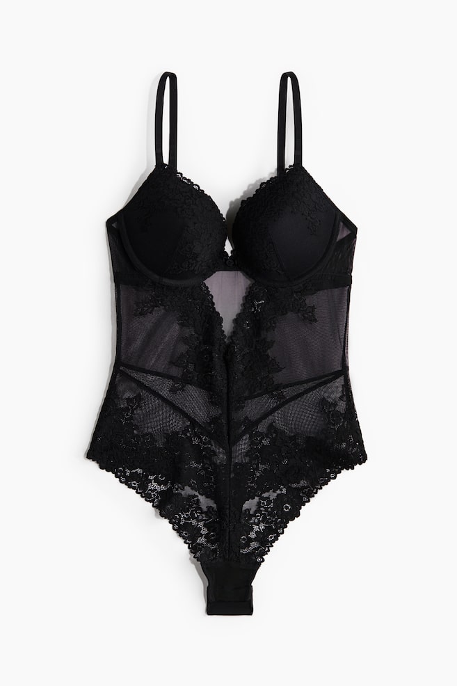 Een zwart kanten en mesh bodysuit wordt van de VOORKANT gepresenteerd, met gestructureerde bh-cups met kantoverlay en verstelbare schouderbandjes. Het lichaam is ontworpen met doorschijnende mesh-panelen, ingewikkelde bloemenkantapplicaties en geometrische lijndetails, eindigend in een stringbodem met kantafwerking. - 1