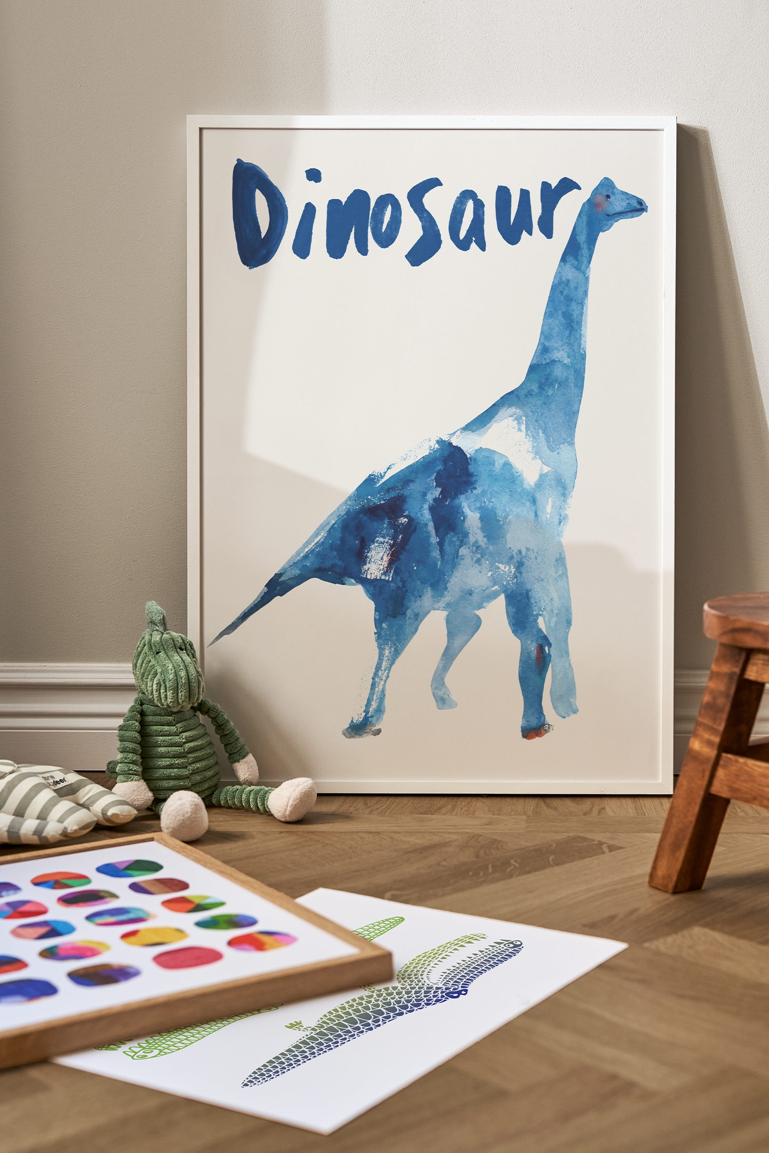 Een kunstprint toont een aquarelillustratie van een dinosaurus met een lange nek, naar rechts gericht, weergegeven in blauwtinten op een gebroken witte achtergrond. Het woord "Dinosaur" verschijnt bovenaan de print in gestileerde blauwe penseelstreken.