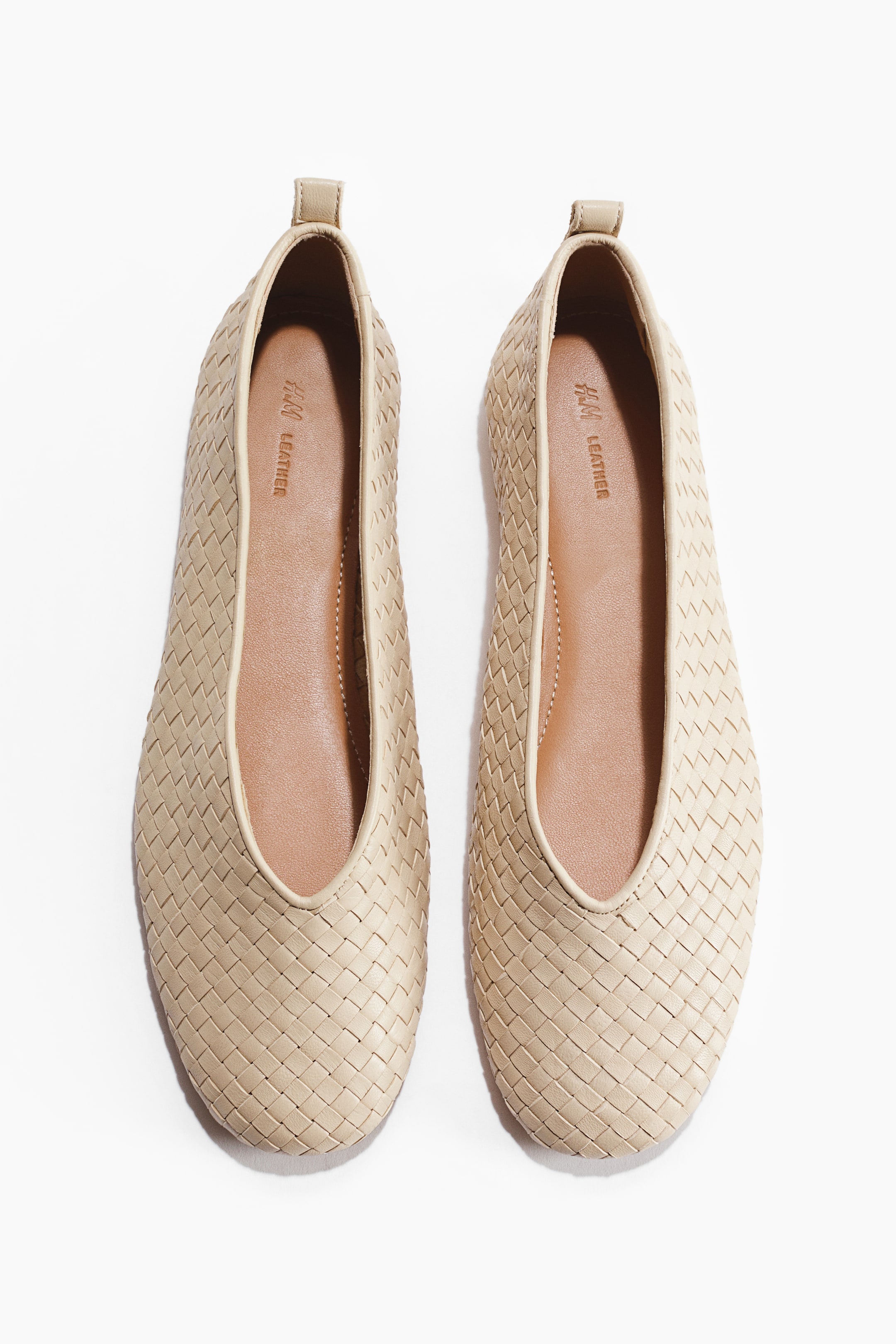 View larger image: A pair of light beige ballet flats is displayed, facing forward. They feature braided leather uppers with rounded toes, a V-shaped topline, a loop at the back, and leather linings and insoles.