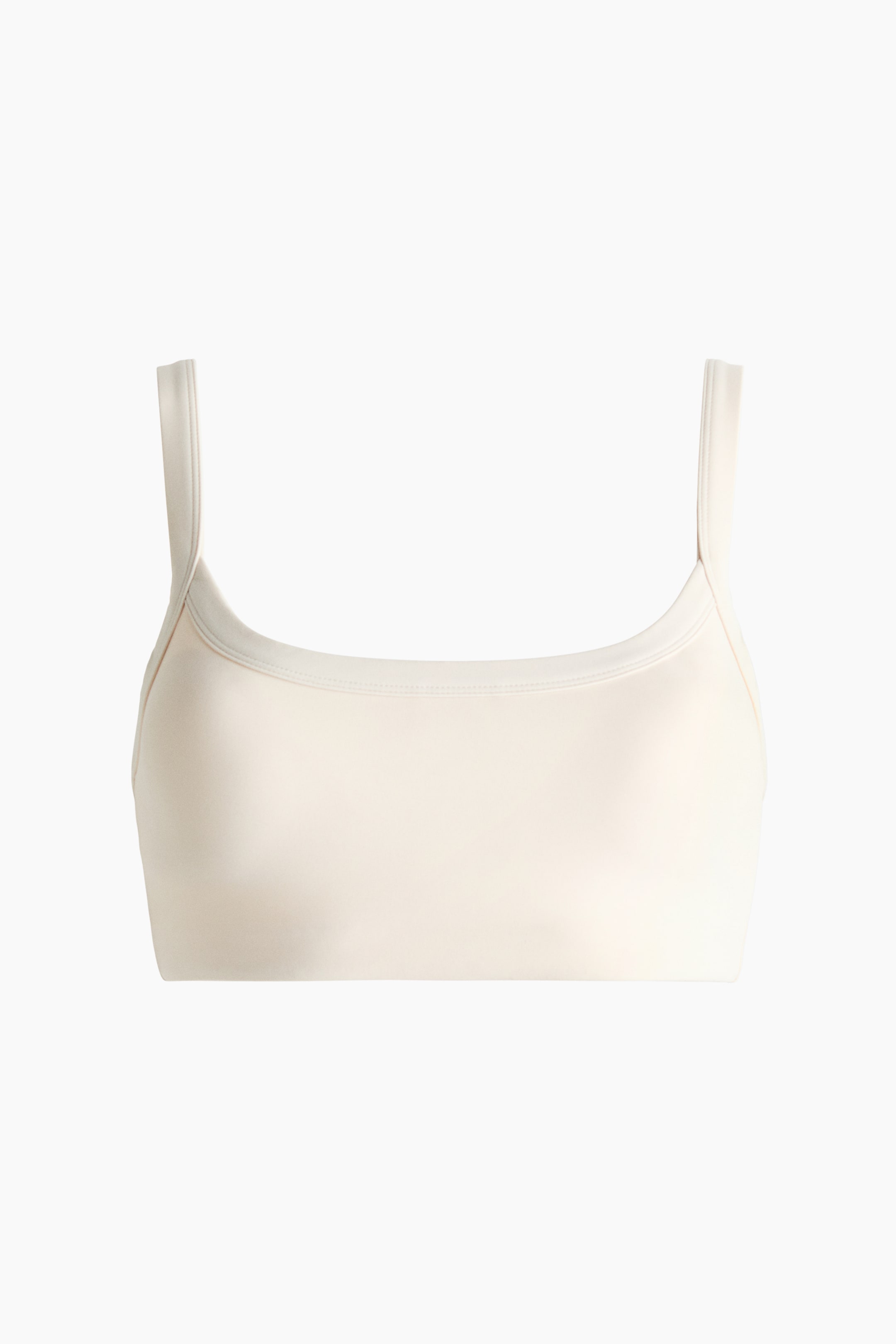 View larger image: The light beige bralette is facing forward, displaying a smooth fabric, wide straps, a square neckline, and a straight bottom hem.