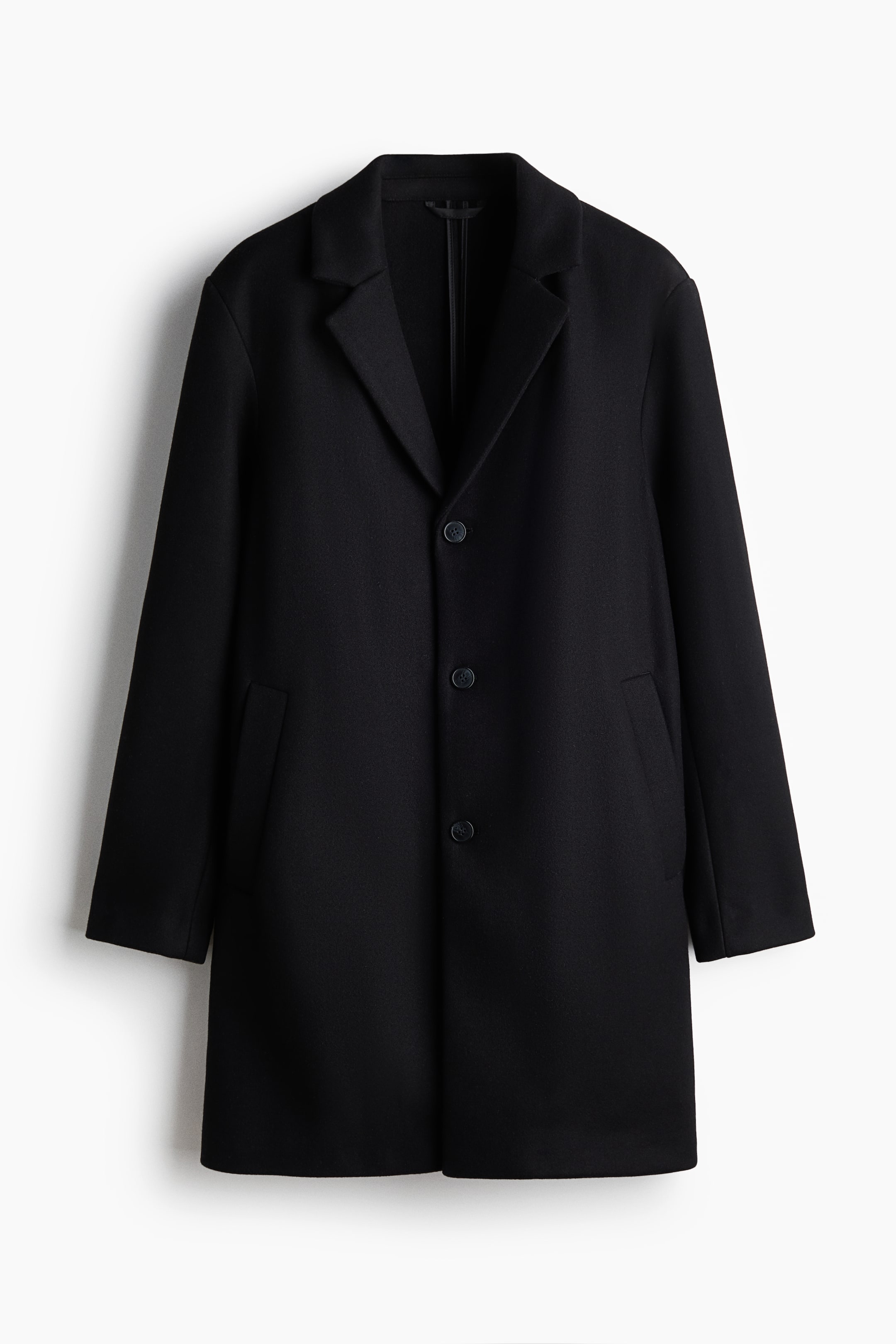 View larger image: A black single-breasted coat features notch lapels, a three-button front, and two jetted pockets.