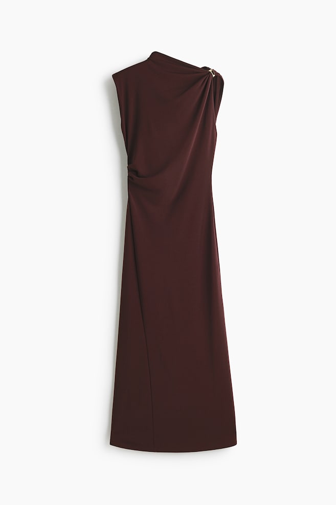 A long, sleeveless dress in dark burgundy heavy interlock jersey showcases its slim fit and asymmetric design. It features a draped detail with a gold-toned metal ring on the right shoulder and a gathered side seam on the left, creating a draped effect on the bodice. - 1