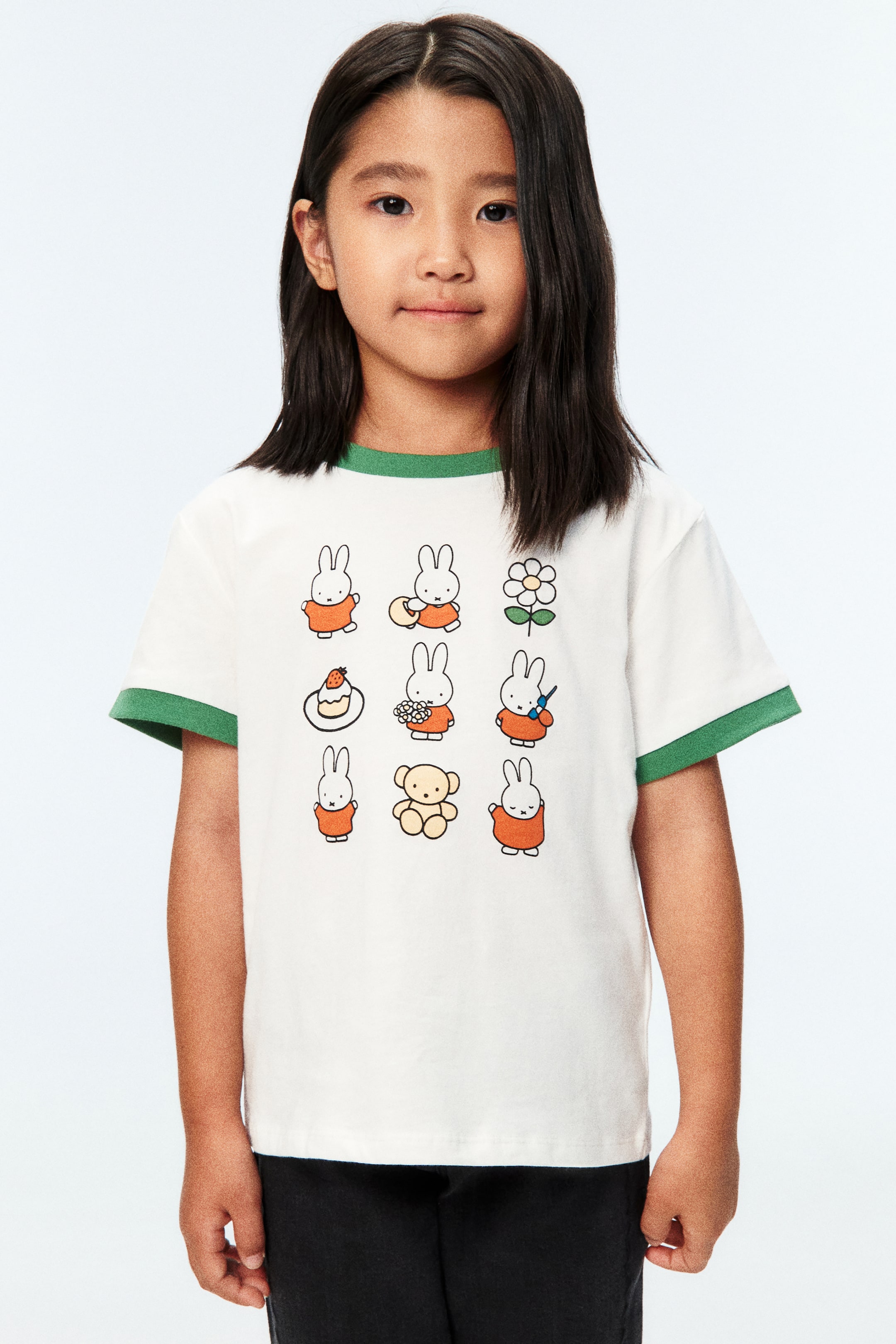 View larger image: A white T-shirt in soft cotton jersey, featuring a print motif of Miffy characters and a teddy bear on the front, is worn by the model. It has a round neckline with a contrasting green trim and short sleeves with matching green trims at the cuffs.