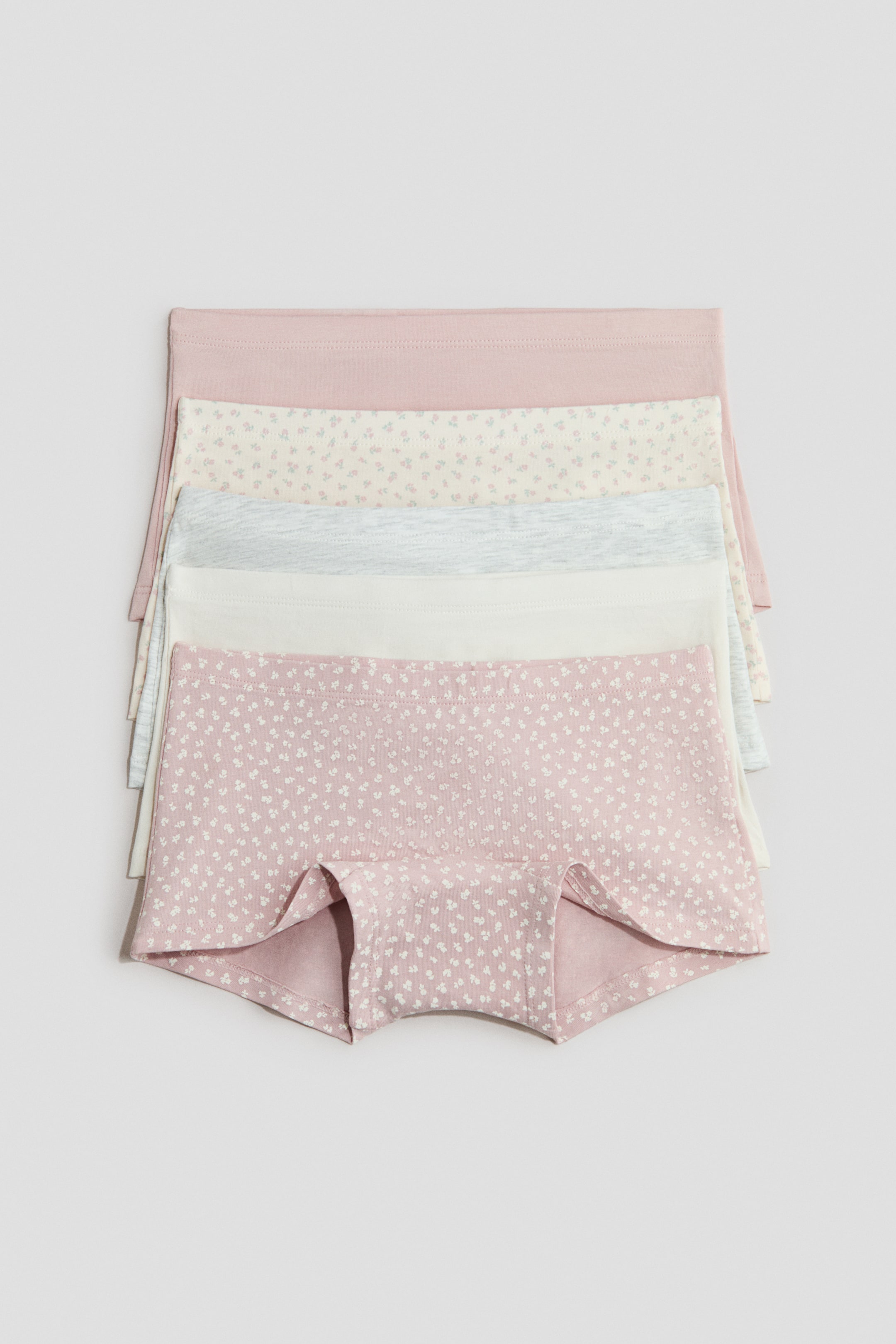 Visa större bild: Fem par av null är staplade, med den nedersta nullen fullt synlig framifrån. Denna null är rosa med ett litet vitt blommönster, och har en elastisk midja samt en boyshort-modell. De fyra null som är lagrade bakom visar olika pastellfärgade och blommiga mönster.