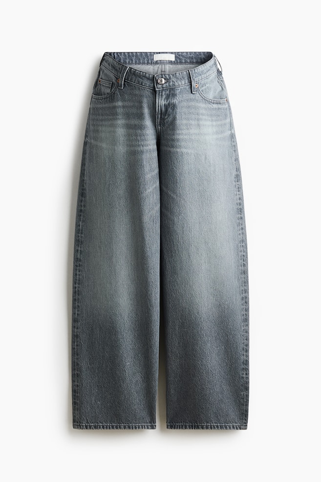 A front view of a pair of wide-leg, five-pocket jeans in a faded grey-blue denim wash. The jeans are featuring a low-rise waist with a button-and-zip fly closure, belt loops, and loose, baggy-fitting straight legs. - 1