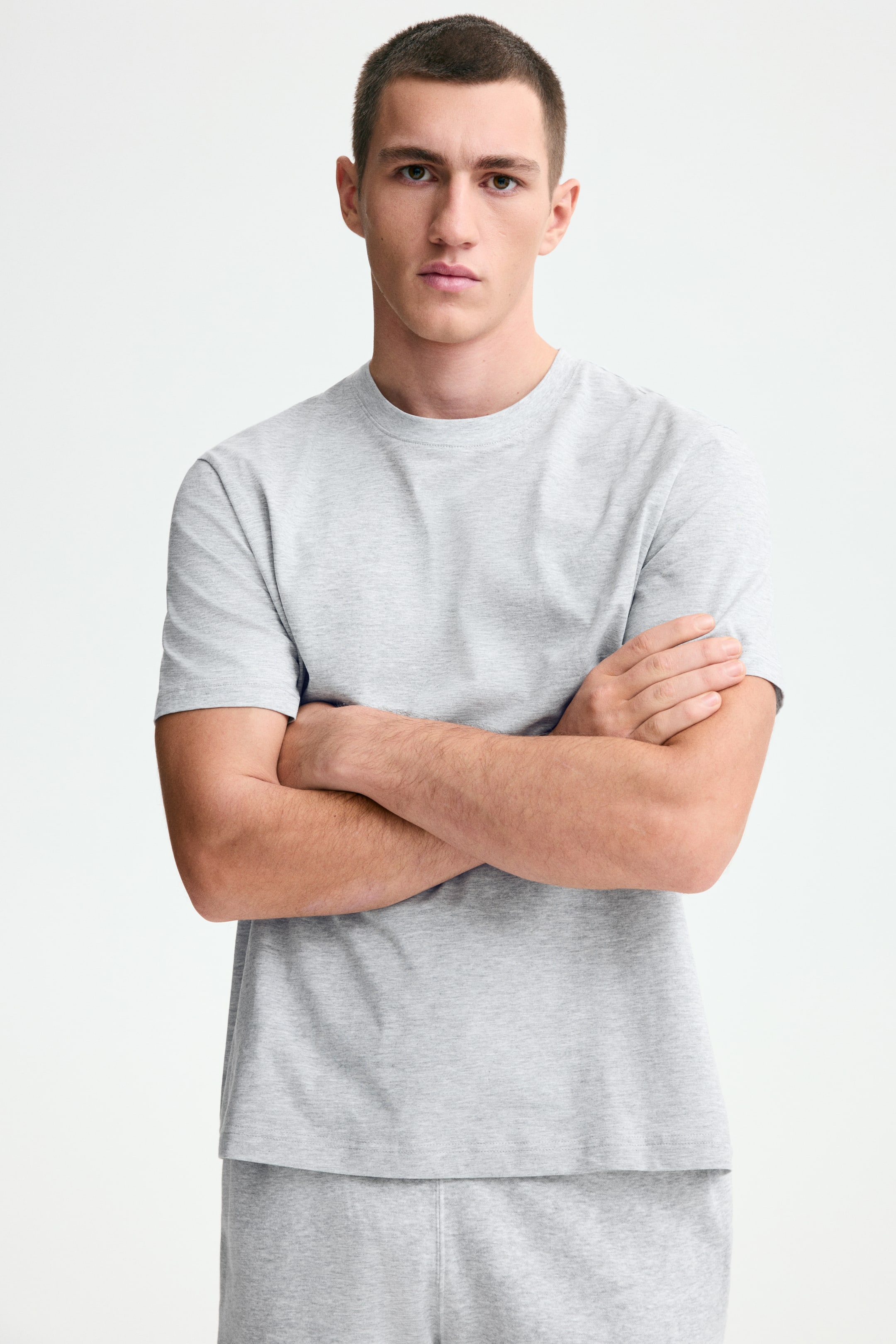 View larger image: A light grey crew neck t-shirt and matching light grey sweatpants are showcased from the front. The t-shirt features short sleeves and a relaxed fit, while the sweatpants display visible vertical seams.
