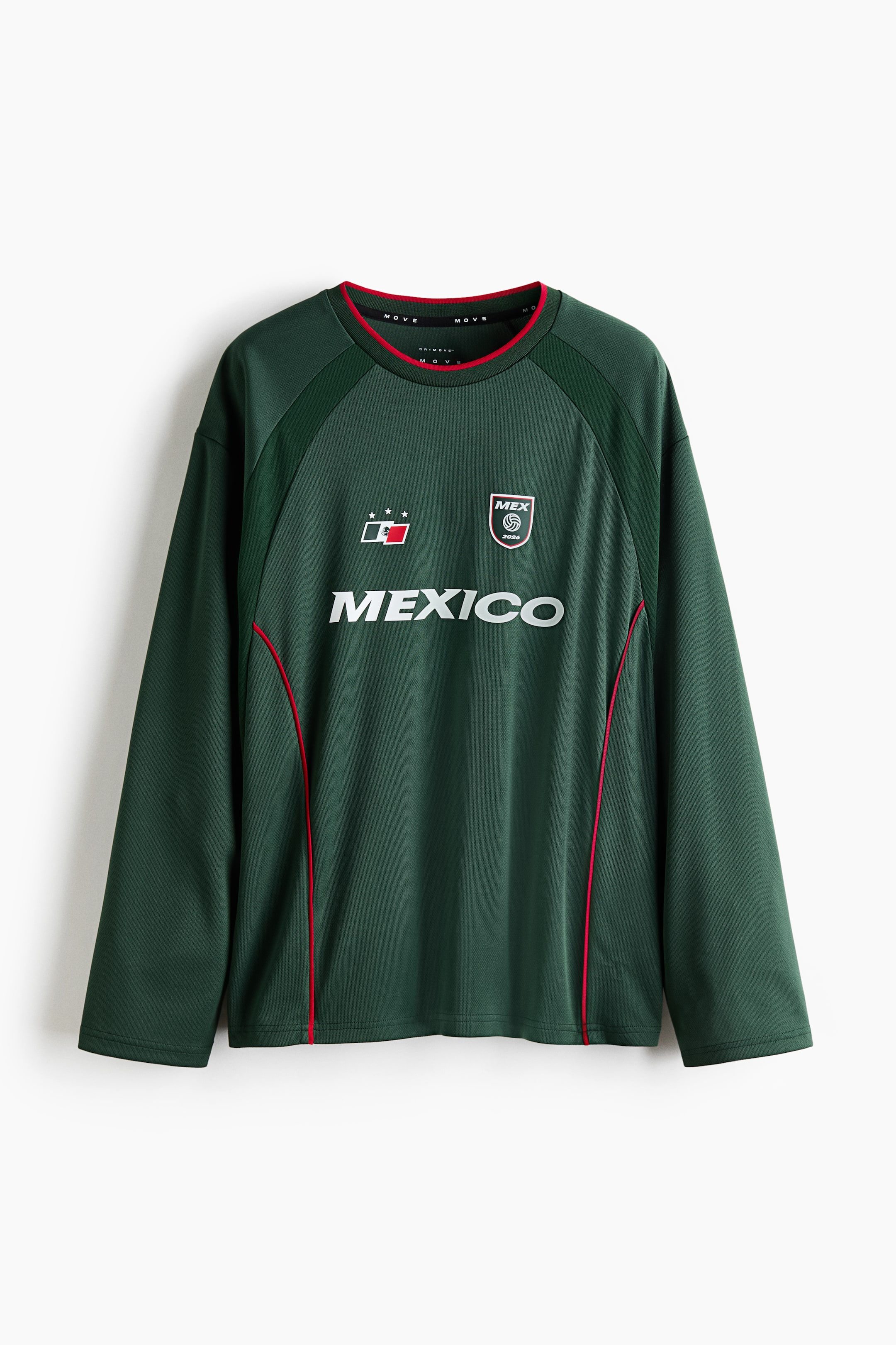 Ampliar la imagen: Una camisa de manga larga verde oscuro muestra su frente, con "MÉXICO" en letras blancas en el pecho. Sobre las letras, un emblema blanco y rojo con dos estrellas está a la izquierda, y un escudo blanco, negro y rojo está a la derecha. También se muestra un cuello redondo con ribete rojo, paneles de hombro raglán de un verde más oscuro, y tuberías verticales rojas en el torso frontal.
