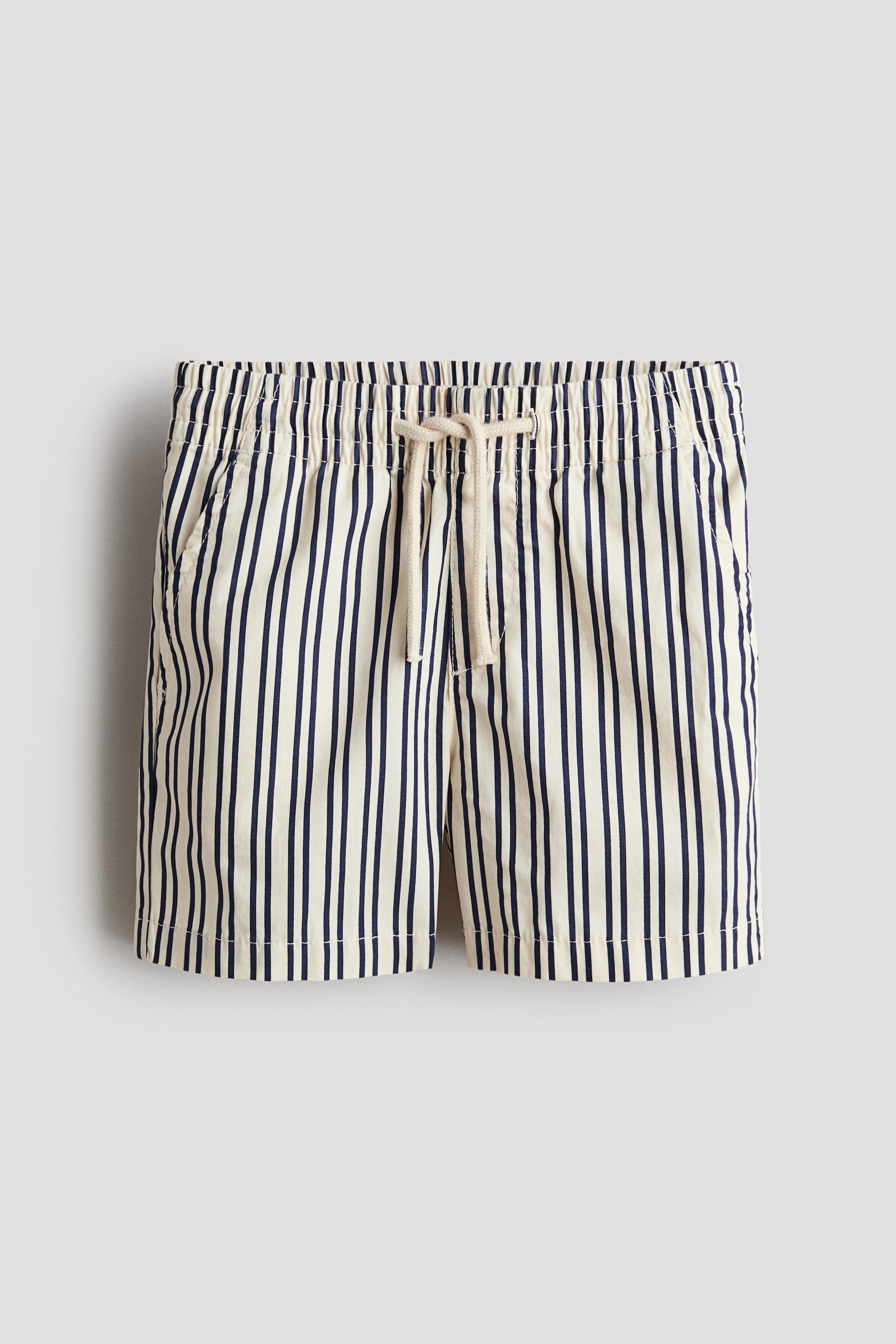View larger image: The shorts are displayed front-facing, showcasing an off-white base with vertical navy stripes. They feature an elasticated waistband, a light-coloured drawstring tied in a bow, and two angled side pockets.