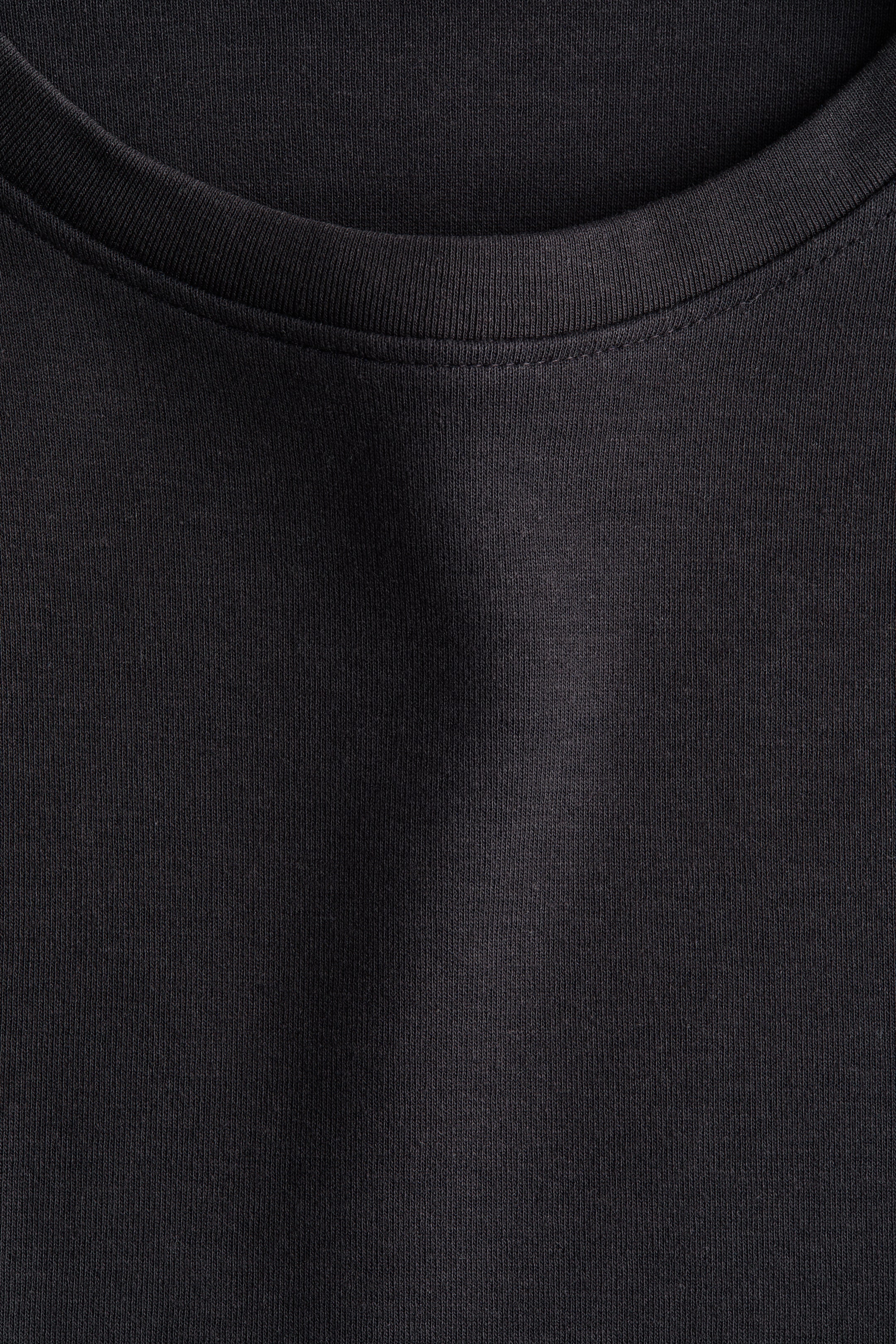 拡大画像を表示: 黒い衣服がその正面を見せており、リブ付きのクルーネックと目に見えるニット生地の質感が特徴です。