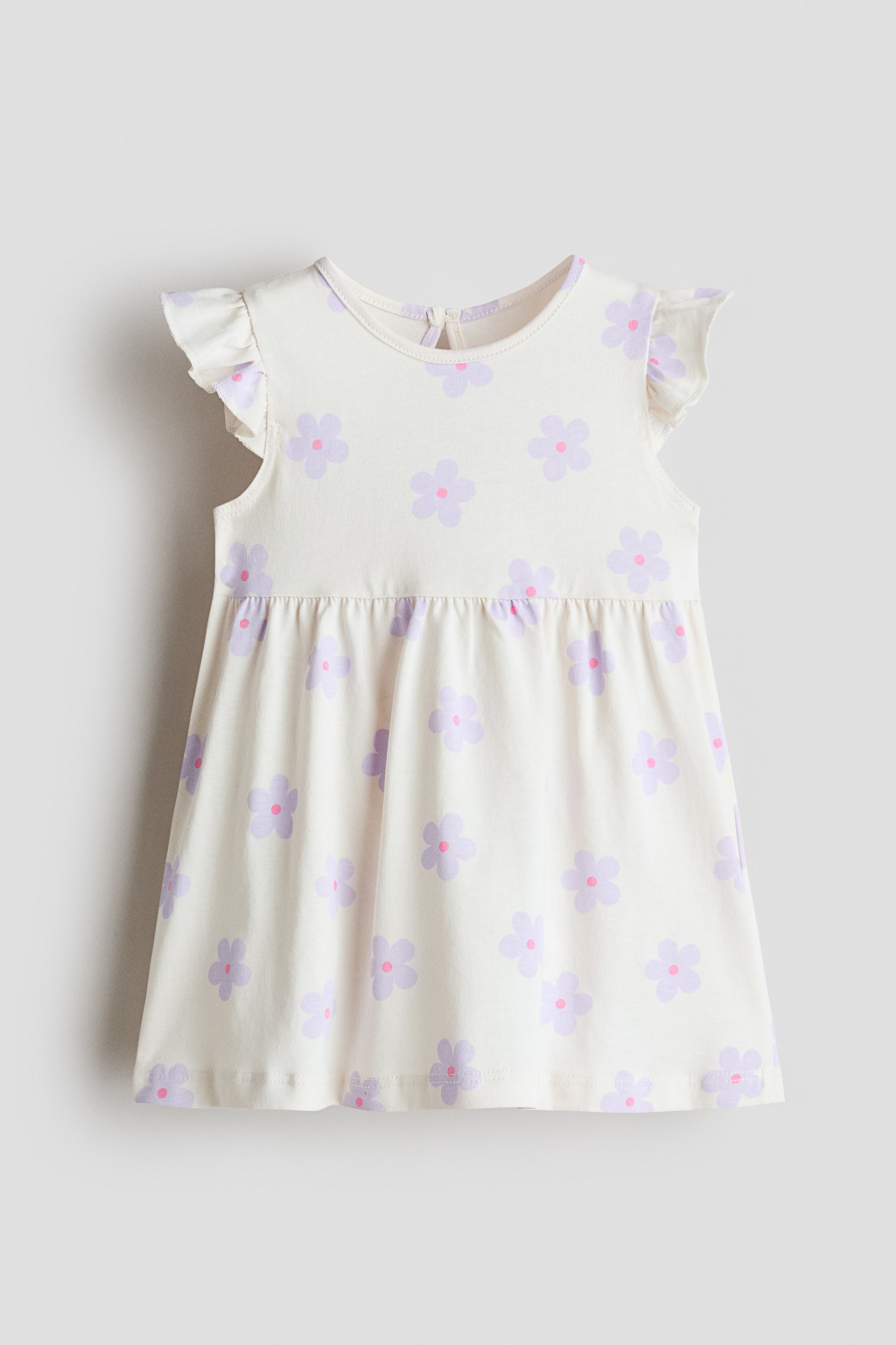 View larger image: This soft, printed cotton jersey dress showcases a cream base adorned with a repeating purple and pink floral pattern, viewed from the front. Designed with a round neckline, flutter sleeves, gathered waist, and a flared skirt, it features a keyhole opening with a button at the back of the neckline.