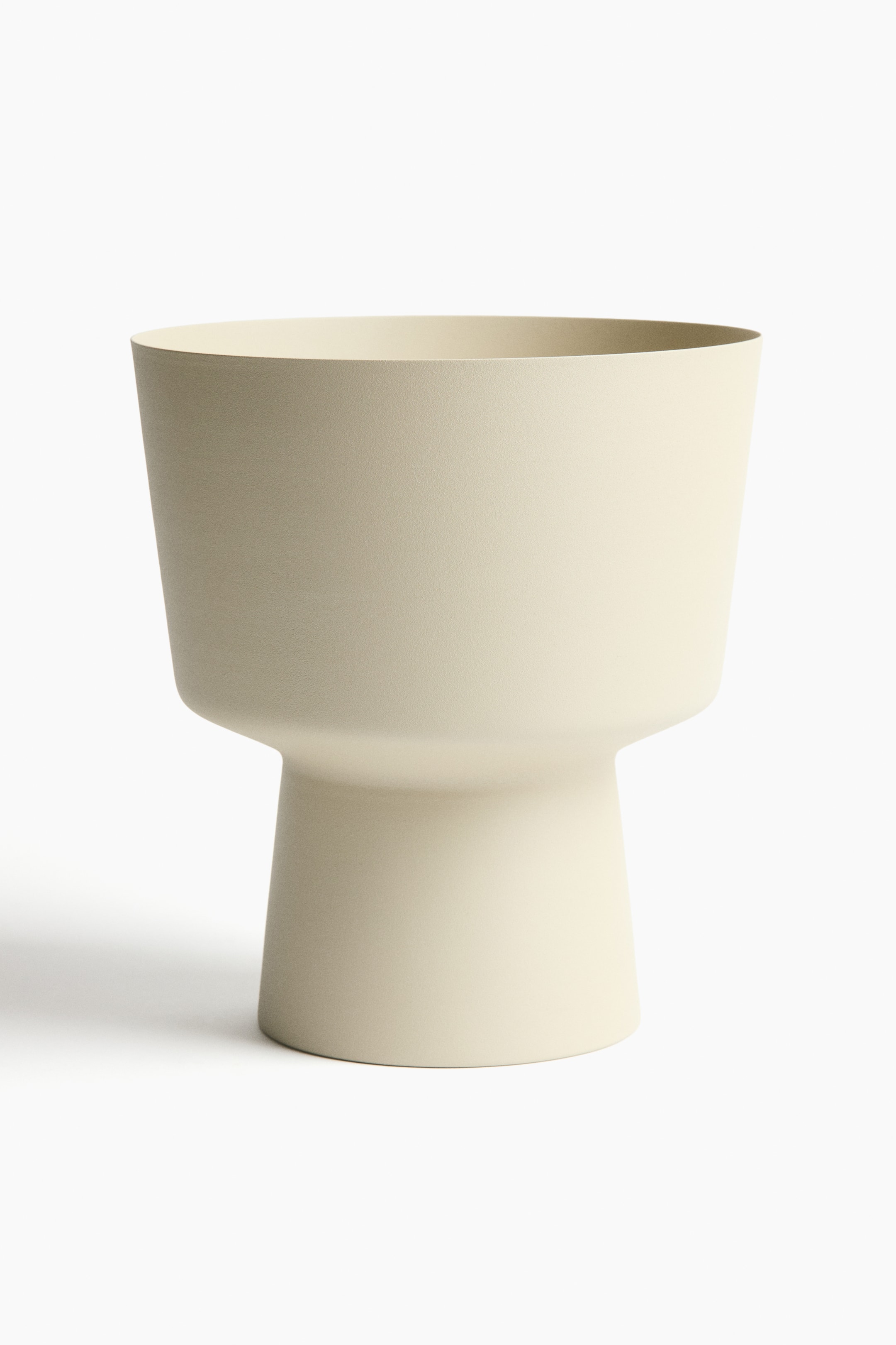 View larger image: The plant pot showcases a broad, open top that gracefully narrows down to a unique pedestal-style base. It boasts a matte, light beige painted metal finish.