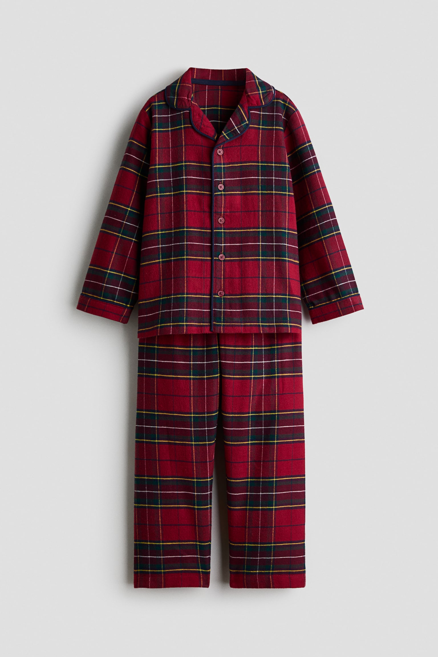 A two-piece red tartan pajama set showcases a classic plaid pattern from the front, consisting of a long-sleeved button-up top and matching straight-leg pants. The top features notch lapels with dark blue piping, a five-button front closure, and long sleeves, while the matching pants hang straight below to complete the set.
