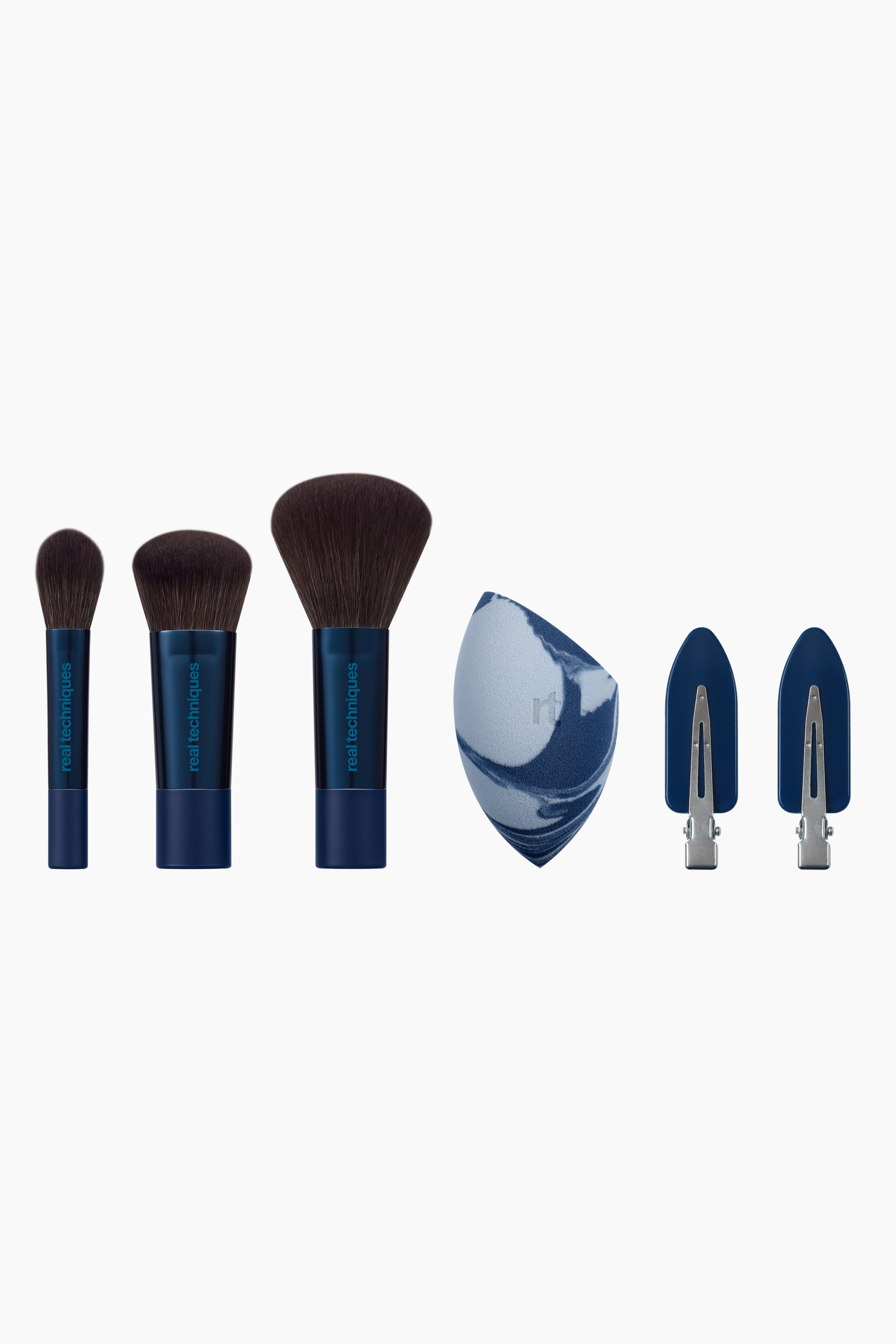 Näytä suurempi kuva: Everyday Slay Brush & Sponge Set -setti sisältää kolme meikkisivellintä, joissa on metallinsiniset varret ja tummanruskeat harjakset, sinivalkoisesti marmoroidun häivytyssienen sekä kaksi sinistä creaseless-hiusklipsiä. Siveltimet on asetettu pystyasentoon koon mukaan kasvavaan järjestykseen, kun taas sienessä näkyy litteä viistottu reuna ja klipseissä hopeiset metallikiinnikkeet.
