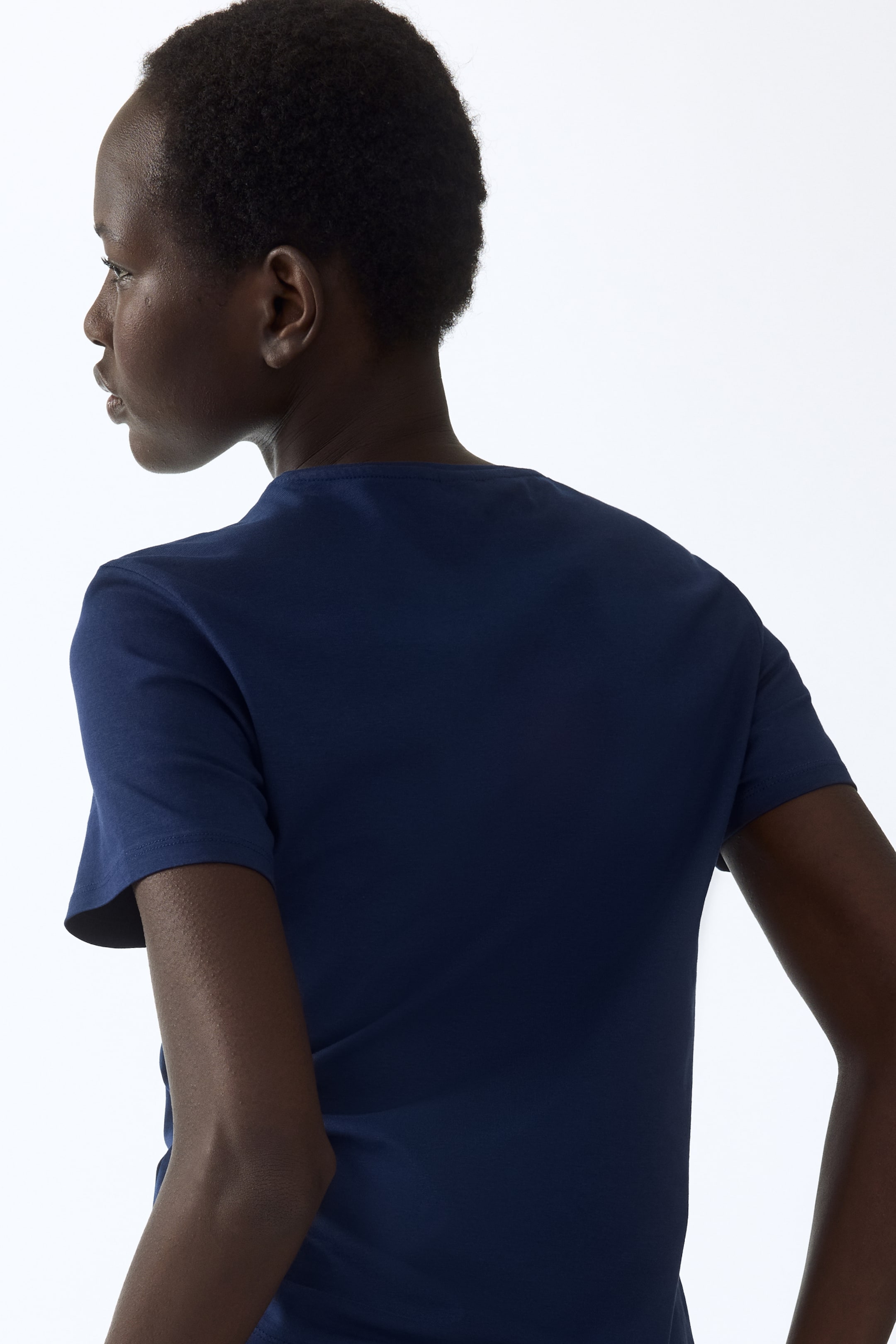 Voir une image plus grande: Un t-shirt bleu marine est présenté de dos, légèrement incliné vers la gauche, affichant un col rond et des manches courtes.