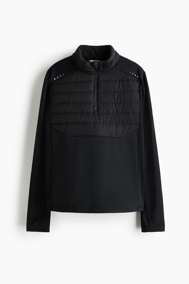 A black athletic quarter-zip top showcasing a quilted front panel across the chest, a high stand collar, and a quarter-zip fastening. It features smooth long sleeves with thumbhole cuffs and small white reflective dots positioned on the upper chest. - 1