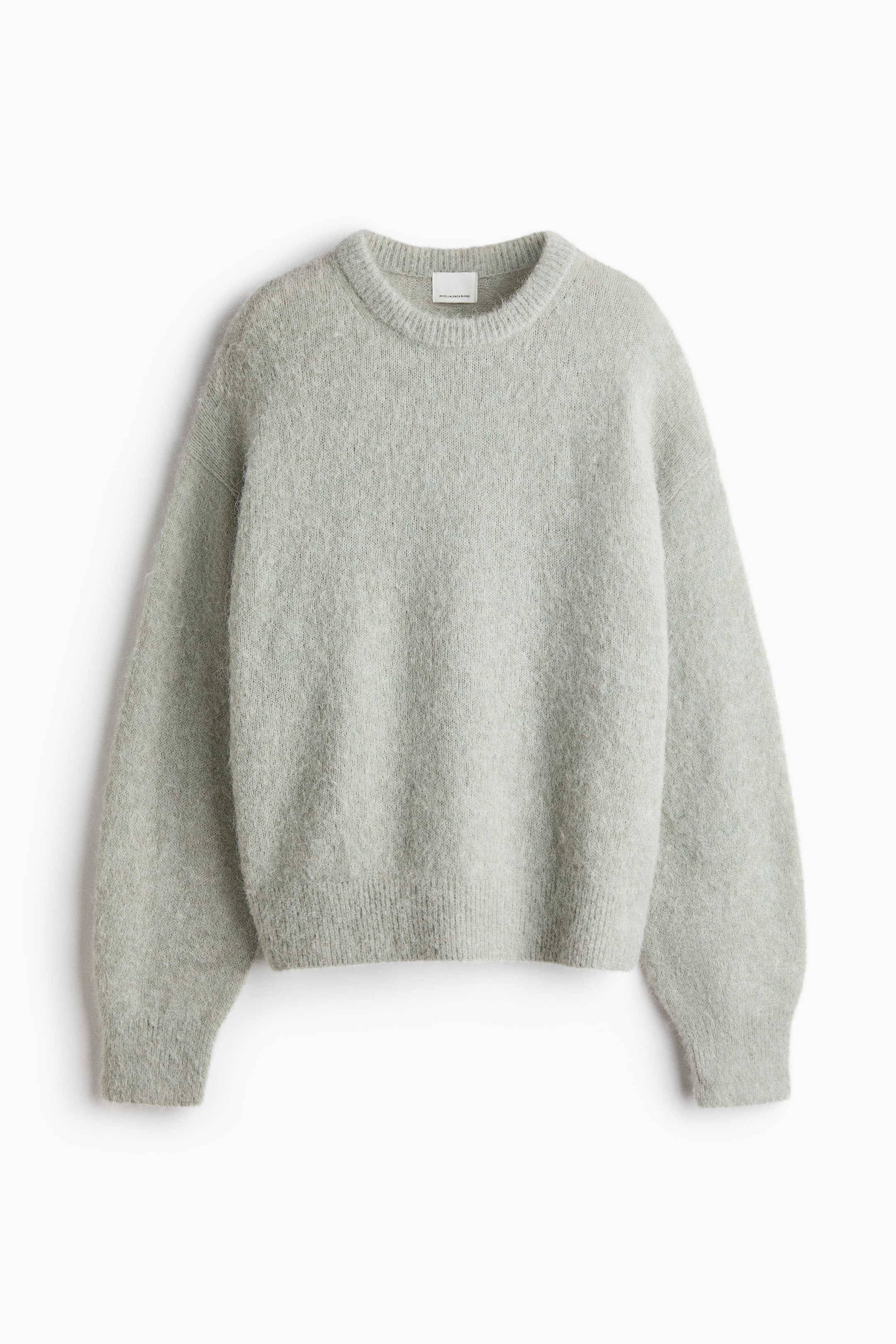 View larger image: An oversized, light sage green knit sweater is shown from the front, showcasing a fuzzy texture, a ribbed crew neck, dropped shoulders, and ribbing at the cuffs and hem.