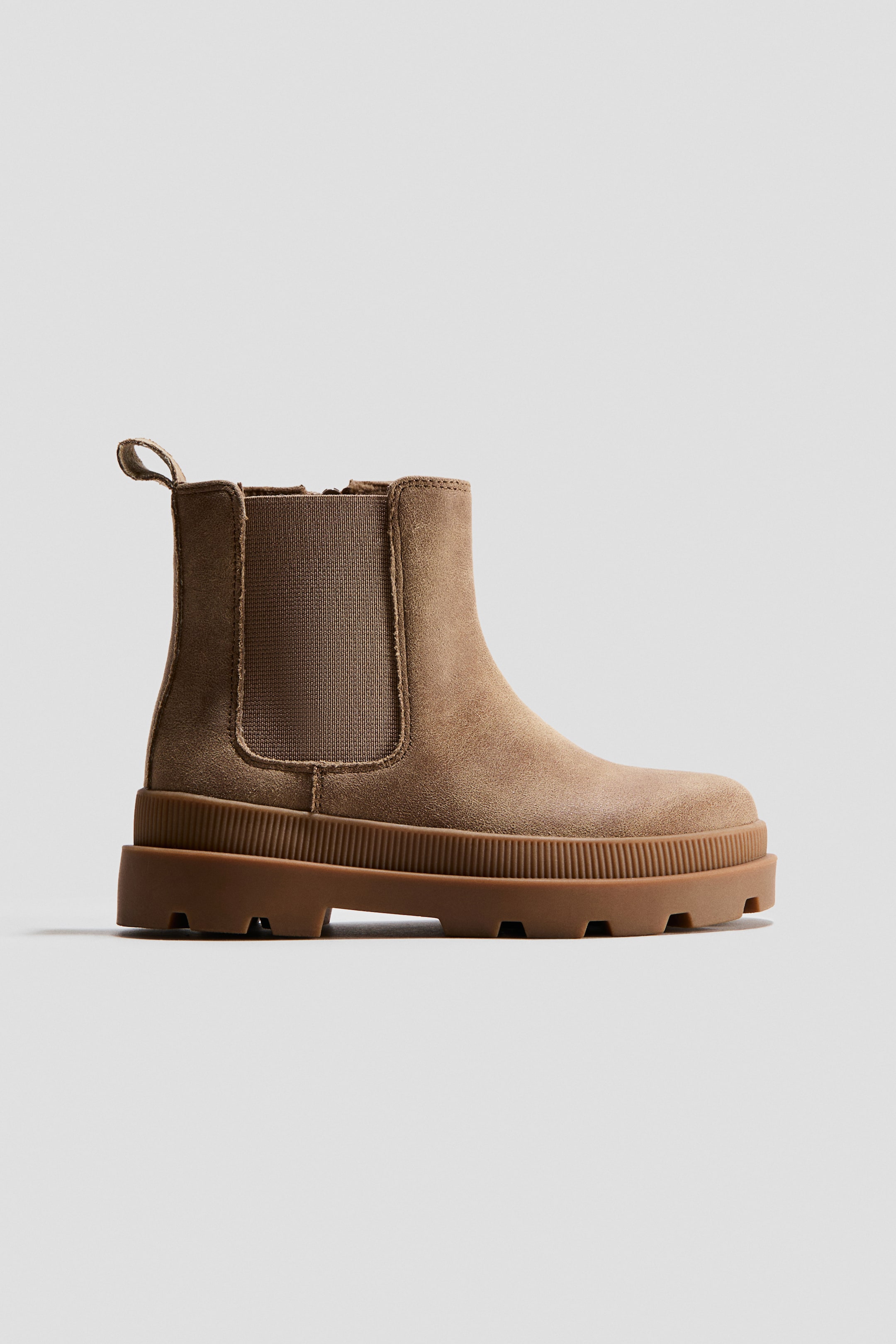 Grotere afbeelding bekijken: Een lichtbruine suède Chelsea-boot staat naar rechts gericht, met elastische zij-inzetten, een treklus aan de achterkant en een stevige profielzool met geribbelde zijdetails.