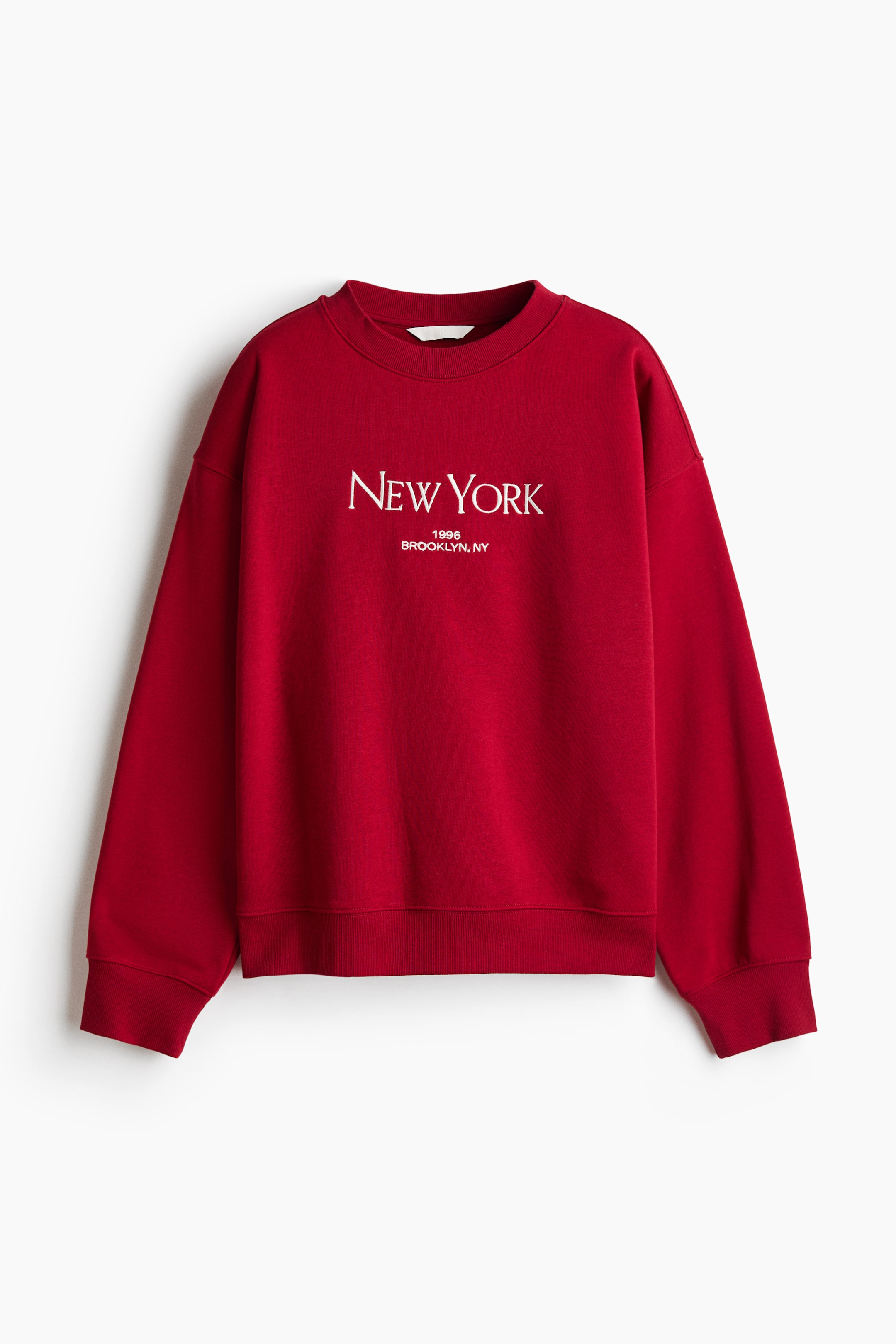 View larger image: A red oversized sweatshirt is shown from the front, featuring a ribbed crew neck, dropped shoulders, and long sleeves with ribbed cuffs and hem. The chest is printed with white text reading "NEW YORK" above "1996" and "BROOKLYN, NY".