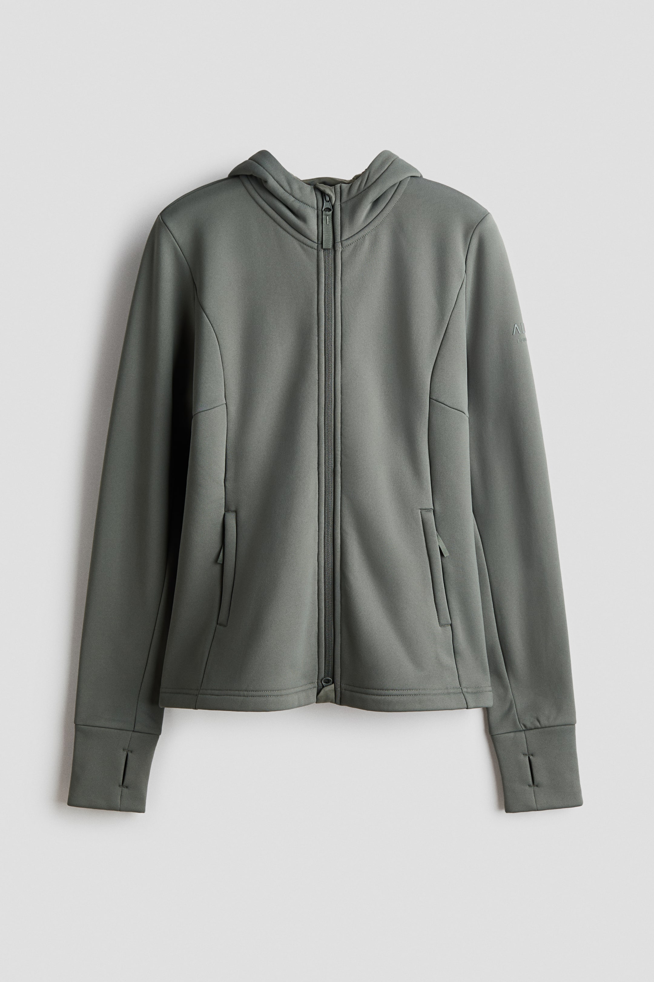 Größeres Bild ansehen: Eine graugrüne Kapuzenjacke mit durchgehendem Reißverschluss präsentiert einen zentralen Verschluss, der bis zum Hals reicht, eine angenähte Kapuze und lange Ärmel. Sie verfügt über Daumenlöcher in den Bündchen und zwei schräg eingesetzte Seitentaschen. Auf dem oberen linken Ärmel befindet sich ein kleines, geprägtes Logo.
