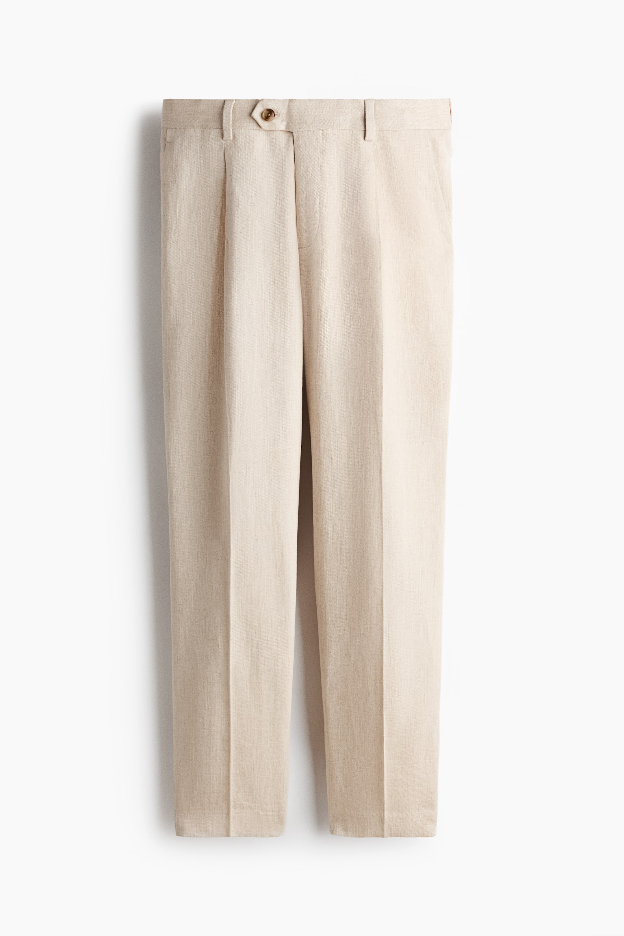 Agrandir l'image: Pantalon beige clair présentant un tissu texturé, doté d'une ceinture plate avec passants pour ceinture, d'une fermeture à bouton marron unique sur une patte pointue, de plis simples à l'avant, de poches latérales et de plis centraux à l'avant descendant le long de chaque jambe.