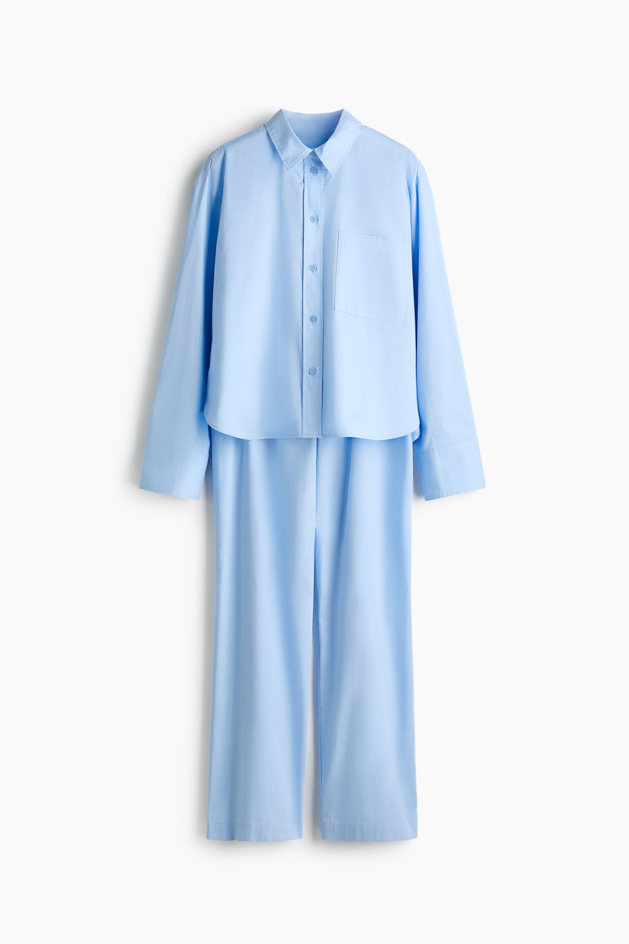 View larger image: Pyjamas in a soft blue cotton weave present a shirt and straight-leg bottoms. The shirt's front features a collar, buttons down the front, a patch chest pocket, gently dropped shoulders and long sleeves with buttoned cuffs, while the bottoms have a smocked, elasticated waist, a mock fly and two decorative buttons at the front.