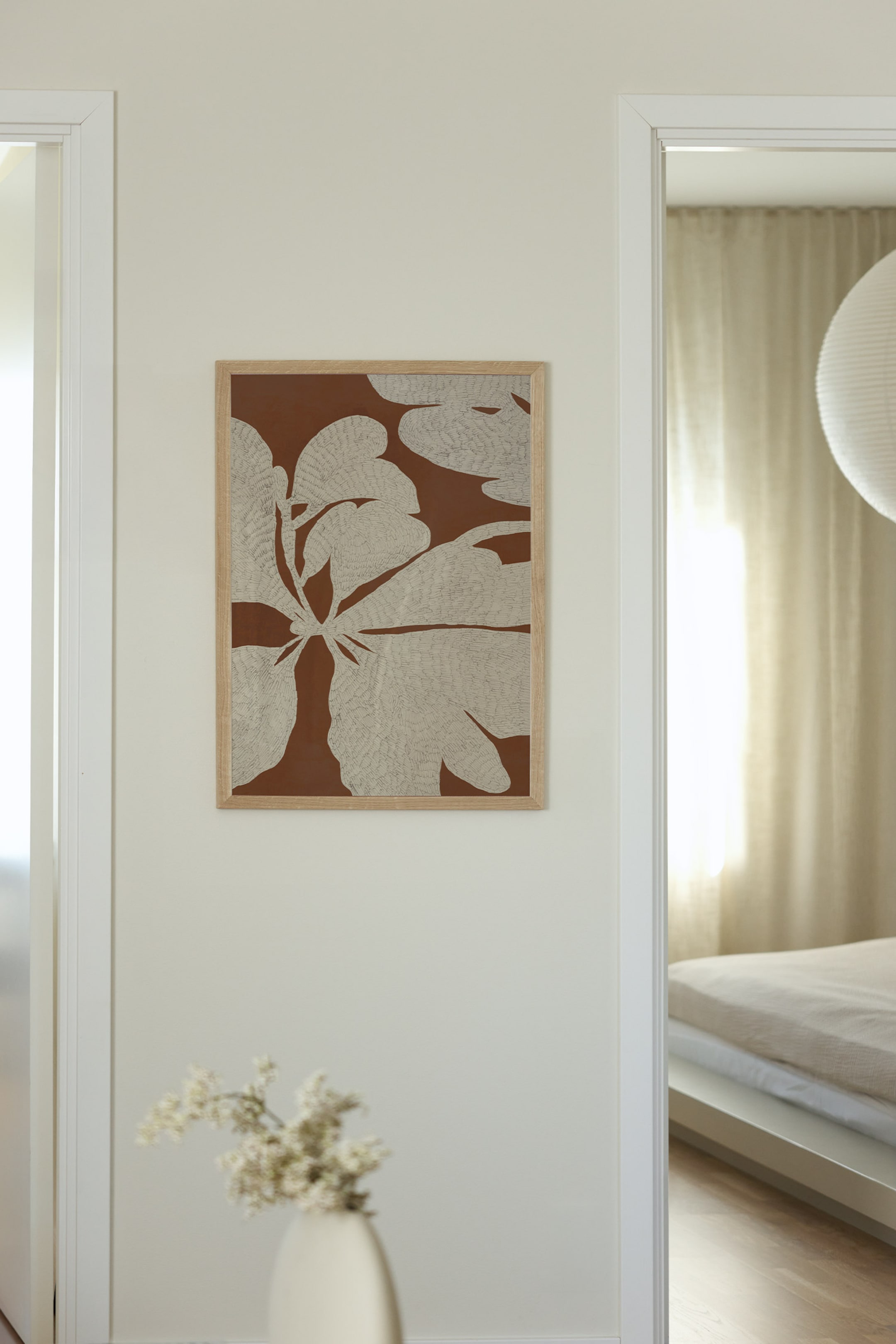 Se større billede: Et indrammet rektangulært kunsttryk viser en stiliseret illustration af store, teksturerede beige blade med fine linjedetaljer på en ensfarvet terrakotta-brun baggrund, indrammet i en lys ramme af naturligt træ.