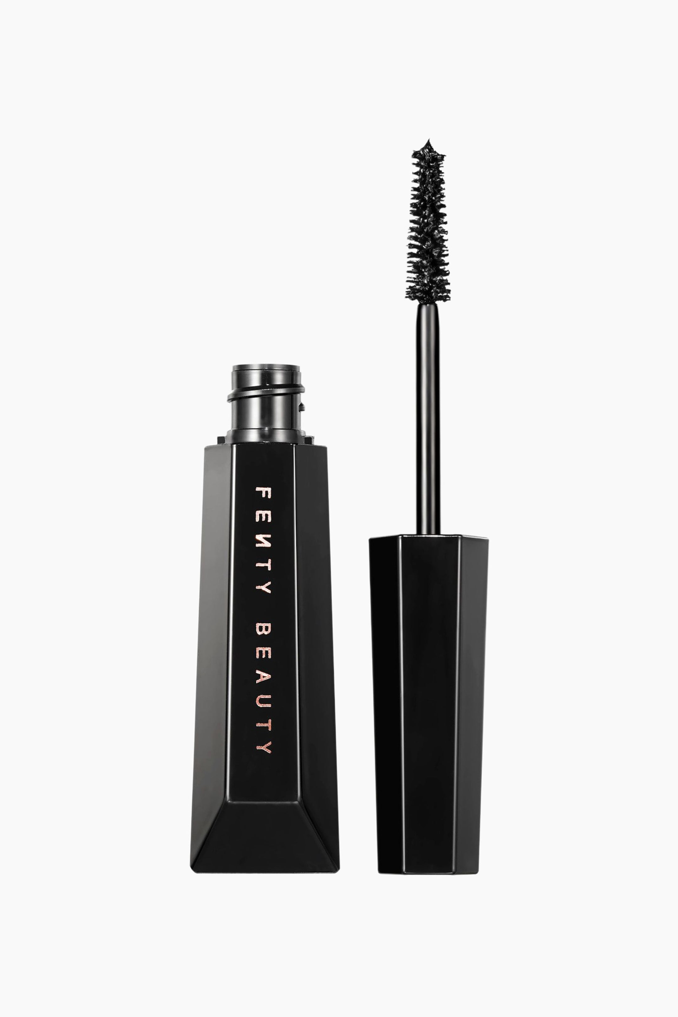 Visa större bild: Hella Thicc Volumizing Mascara visas med sin facetterade svarta geometriska tub stående öppen bredvid den matchande applikatorborsten som är riktad framåt. Tuben visar varumärket vertikalt i metallisk text, medan borsten visar en tät, avsmalnande borstborste täckt med svart mascara.