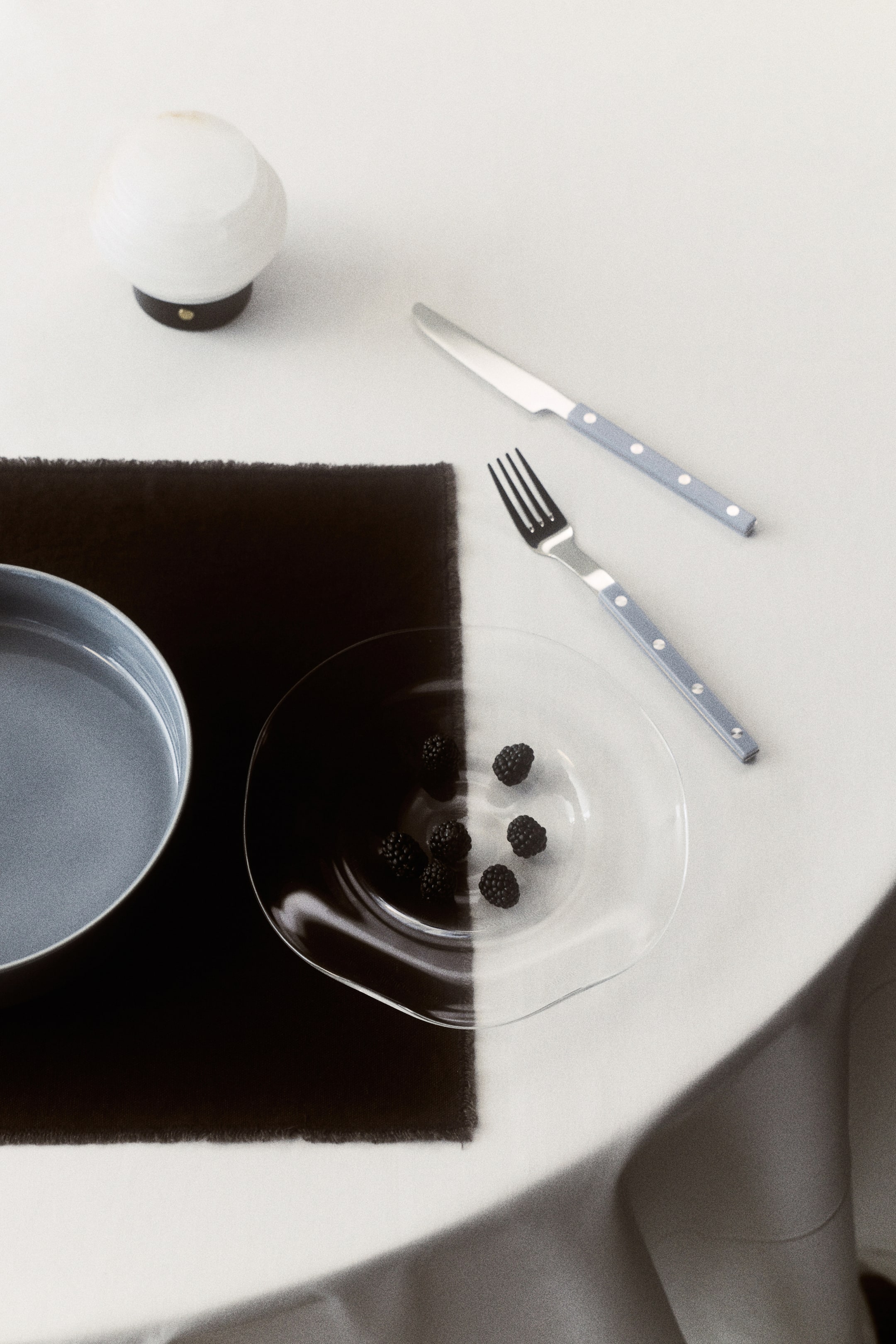 View larger image: A starter plate, crafted from mouth-blown glass, features an irregular, wavy design along its edge. The shallow, clear plate holds several blackberries.