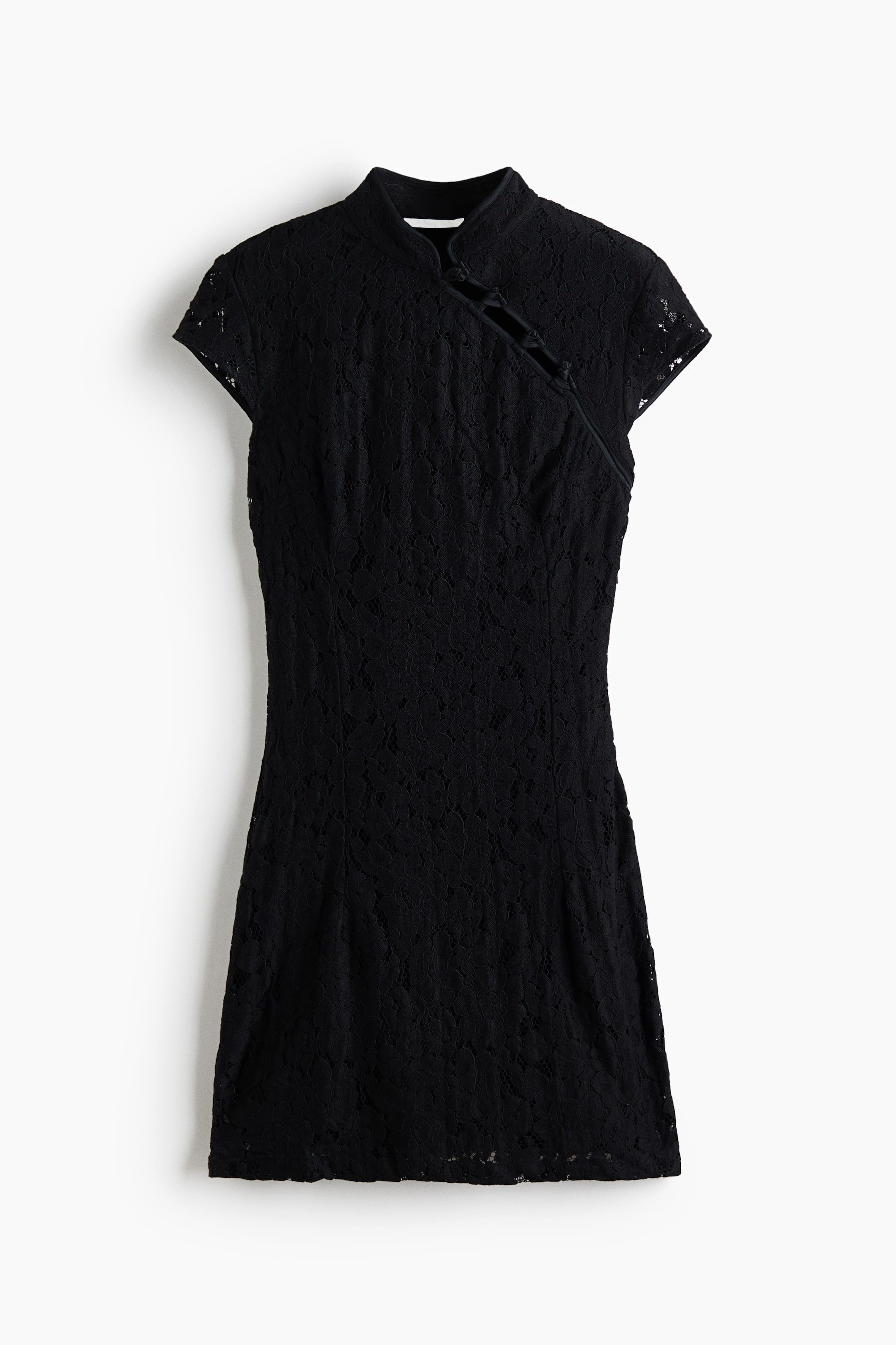 View larger image: A short, fitted black lace dress is shown from the front, featuring a band collar and a diagonal chest opening with decorative knot buttons. The dress has cap sleeves and vertical waist darts that define its structured silhouette.