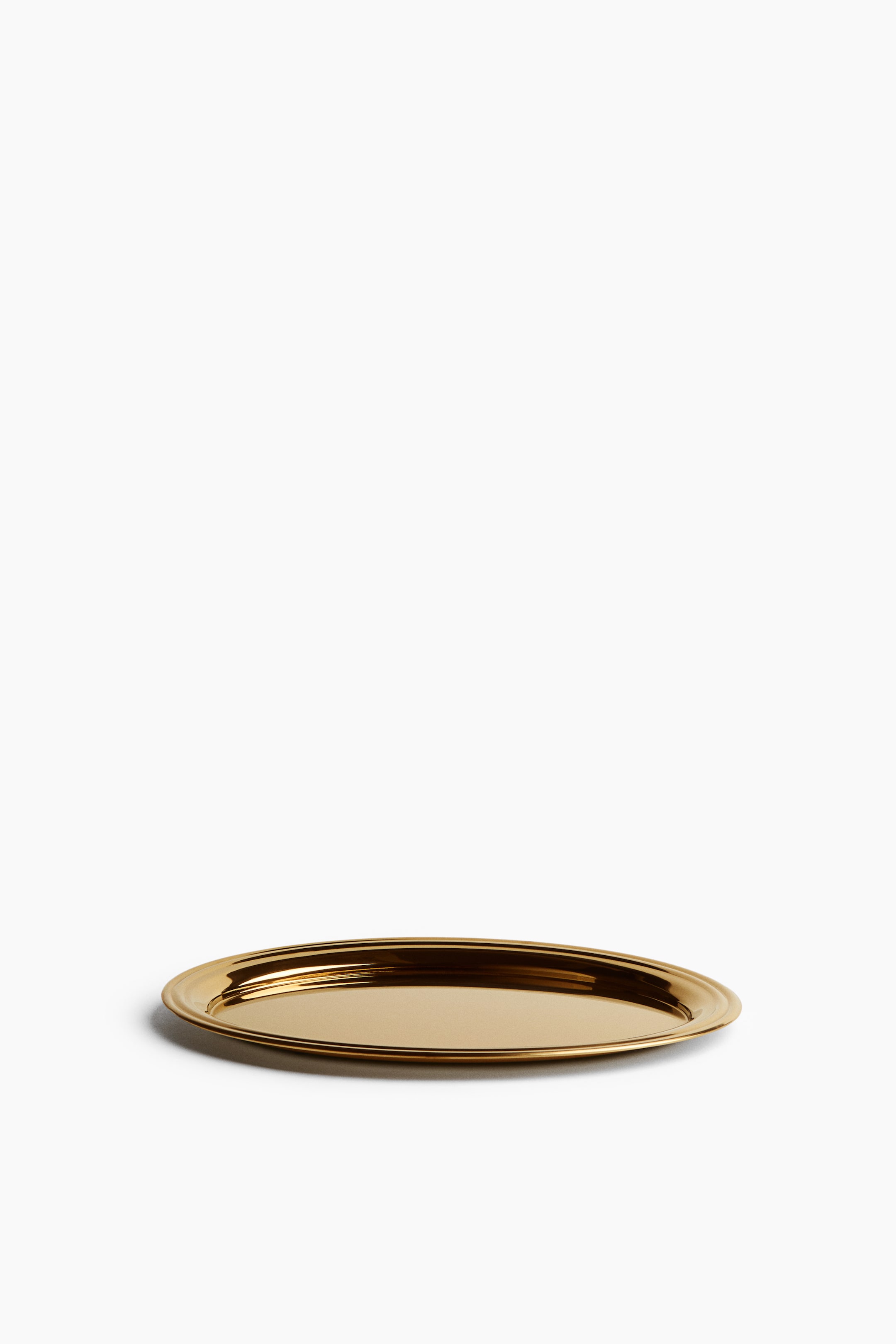 View larger image: An oval tray featuring a polished gold-toned finish rests flat, shown from a slightly elevated front angle. The tray showcases a smooth, reflective central surface bordered by a raised, tiered rim.